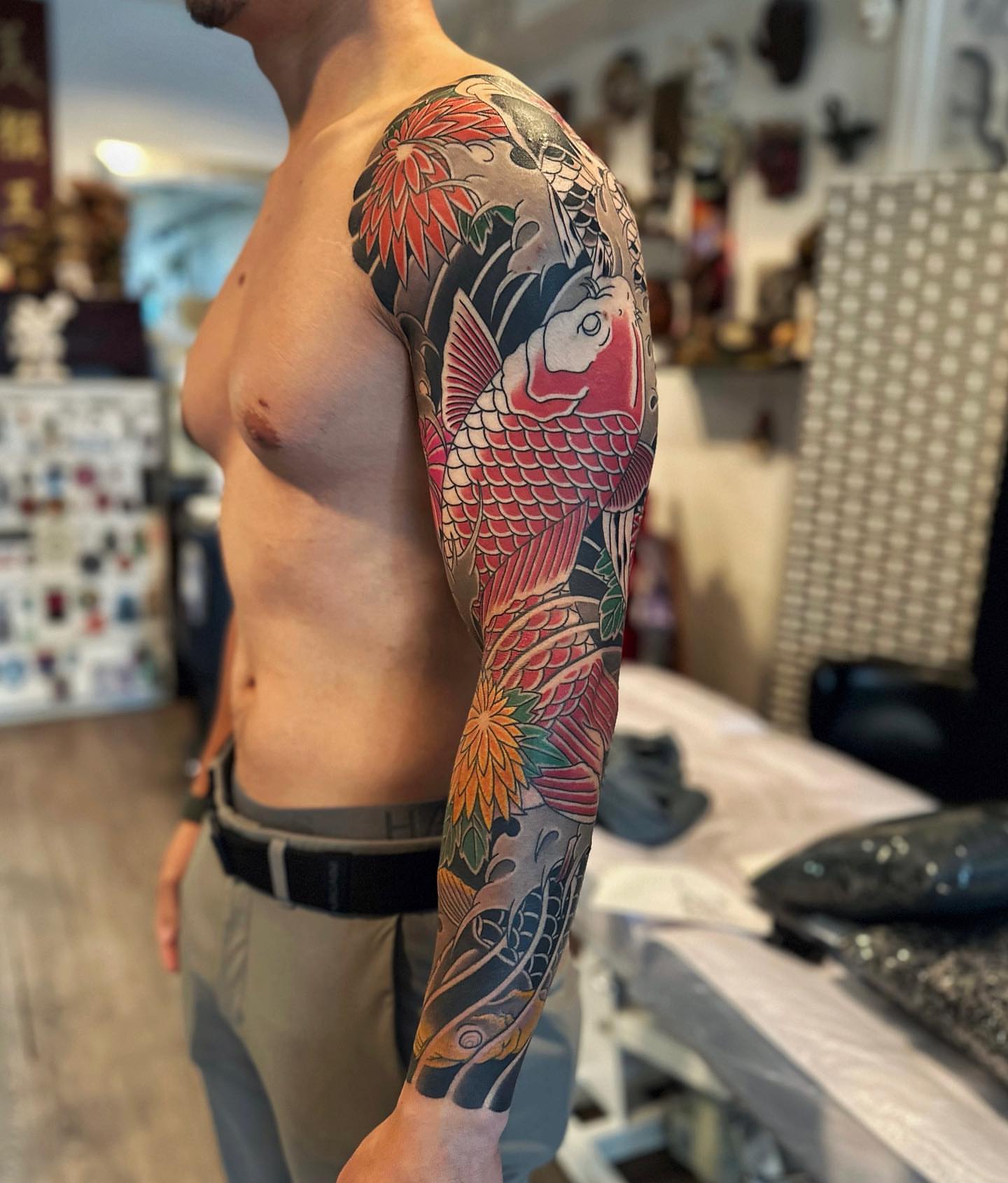Koi fish and chrysanthemum japanese irezumi tattoo on the upper arm by Xiaojun Yin, Vancouver, British Columbia