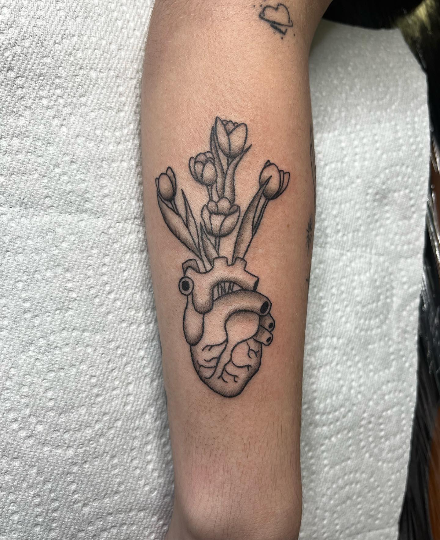 Heart with flowers black and grey tattoo on the forearm by 𝖎𝖘𝖆 ✶ 𝖉𝖋𝖜 𝖙𝖆𝖙𝖙𝖔𝖔𝖘