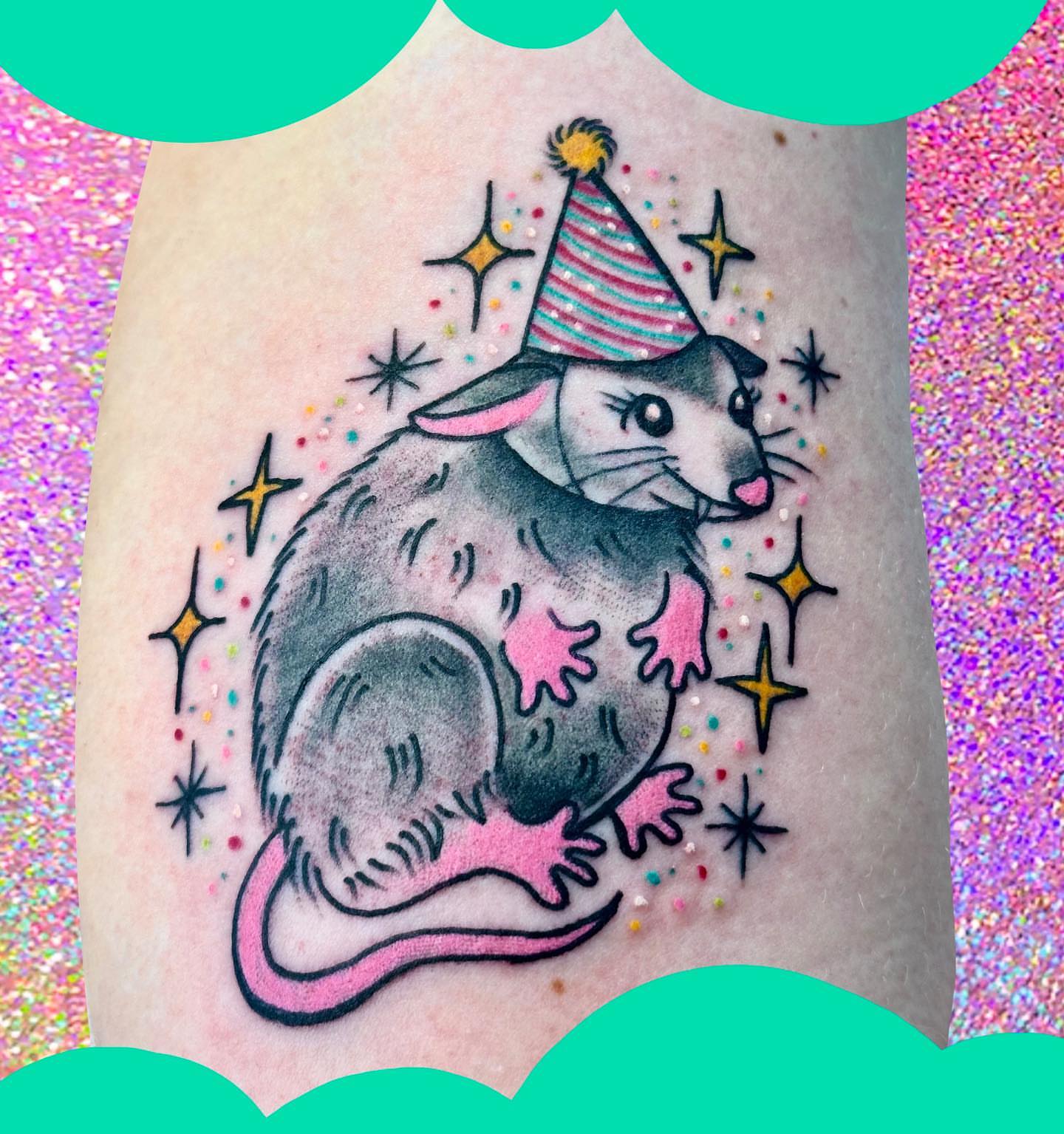 Possum wearing party hat trash polka tattoo on the forearm by Chelsea Lane