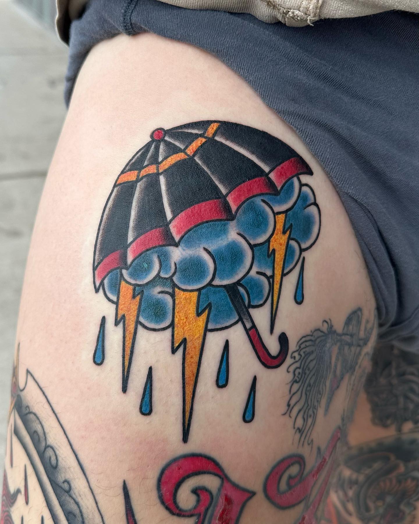 Rain cloud with umbrella American traditional tattoo on the thigh by Zach Eden