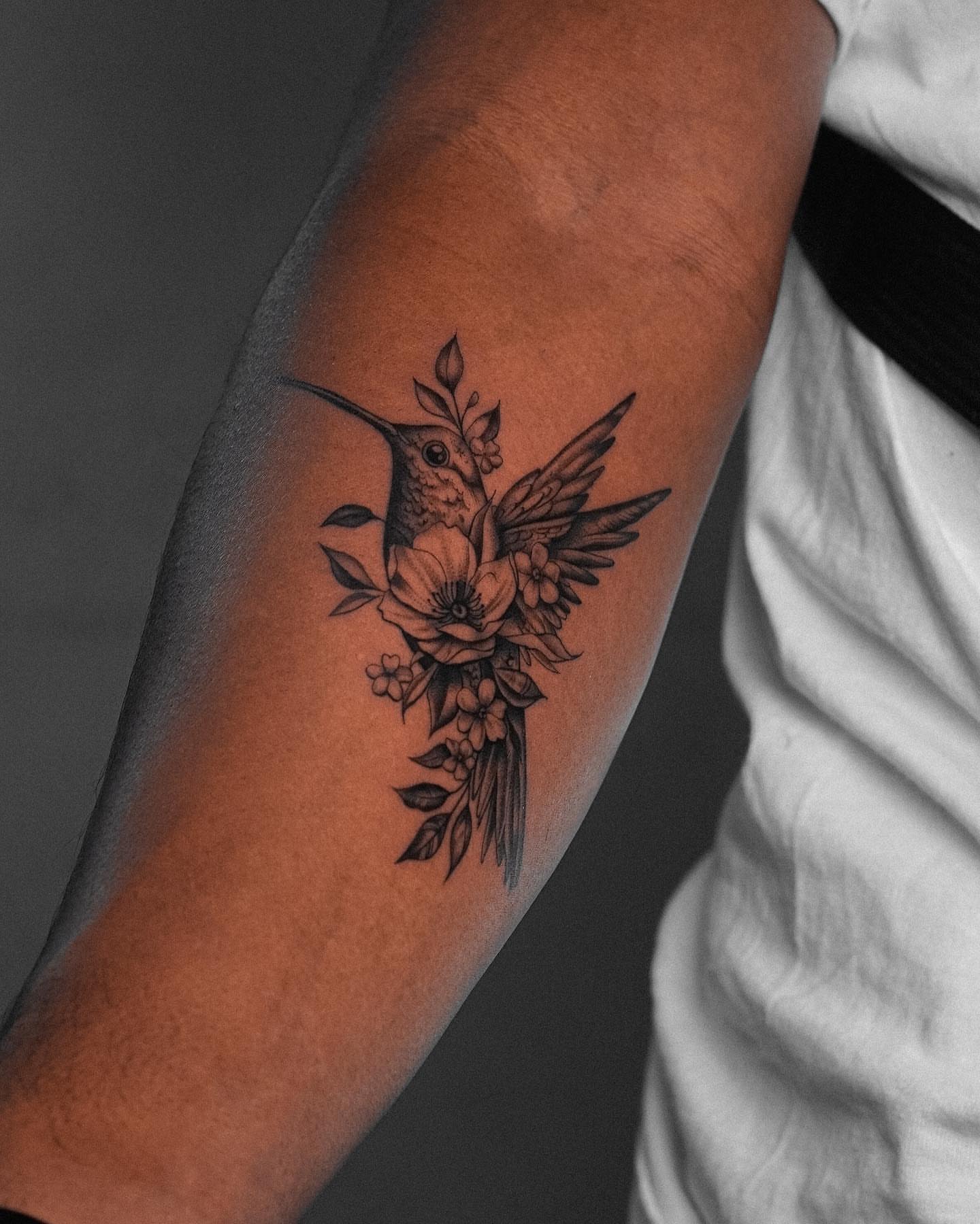 Hummingbird and flowers black and grey tattoo on the forearm by Mateo
