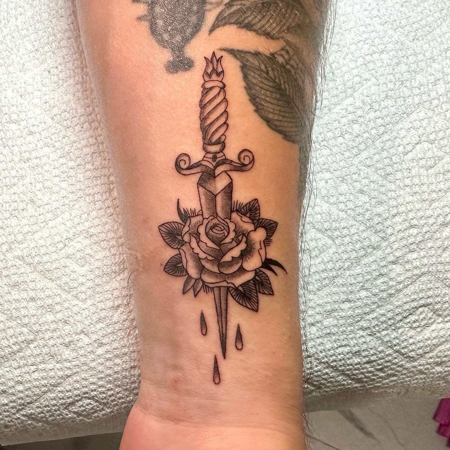 Sword through rose black and grey tattoo on the forearm by Jorden Ruppe