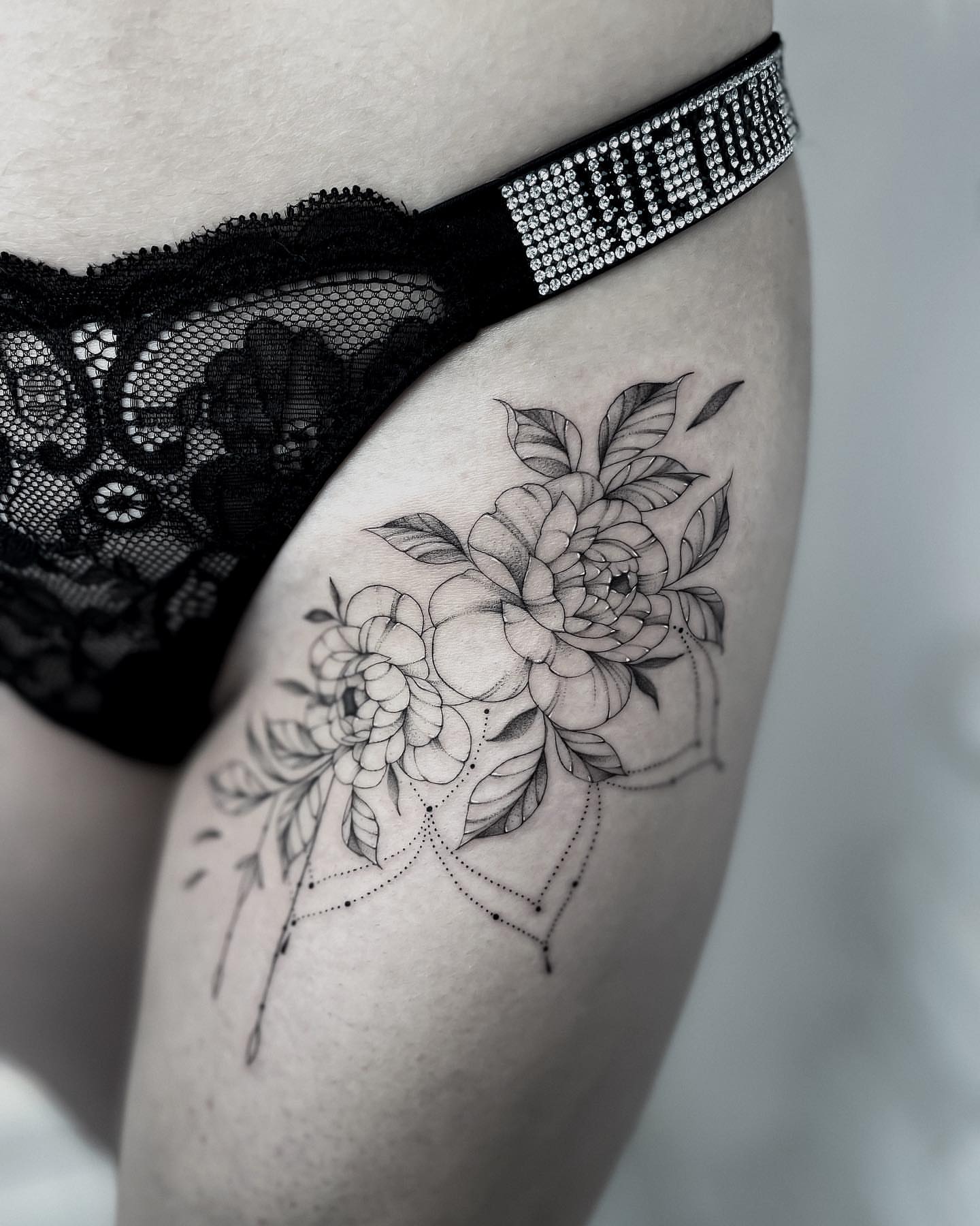 Floral bouquet black and grey tattoo on the thigh by Annie Overchuk