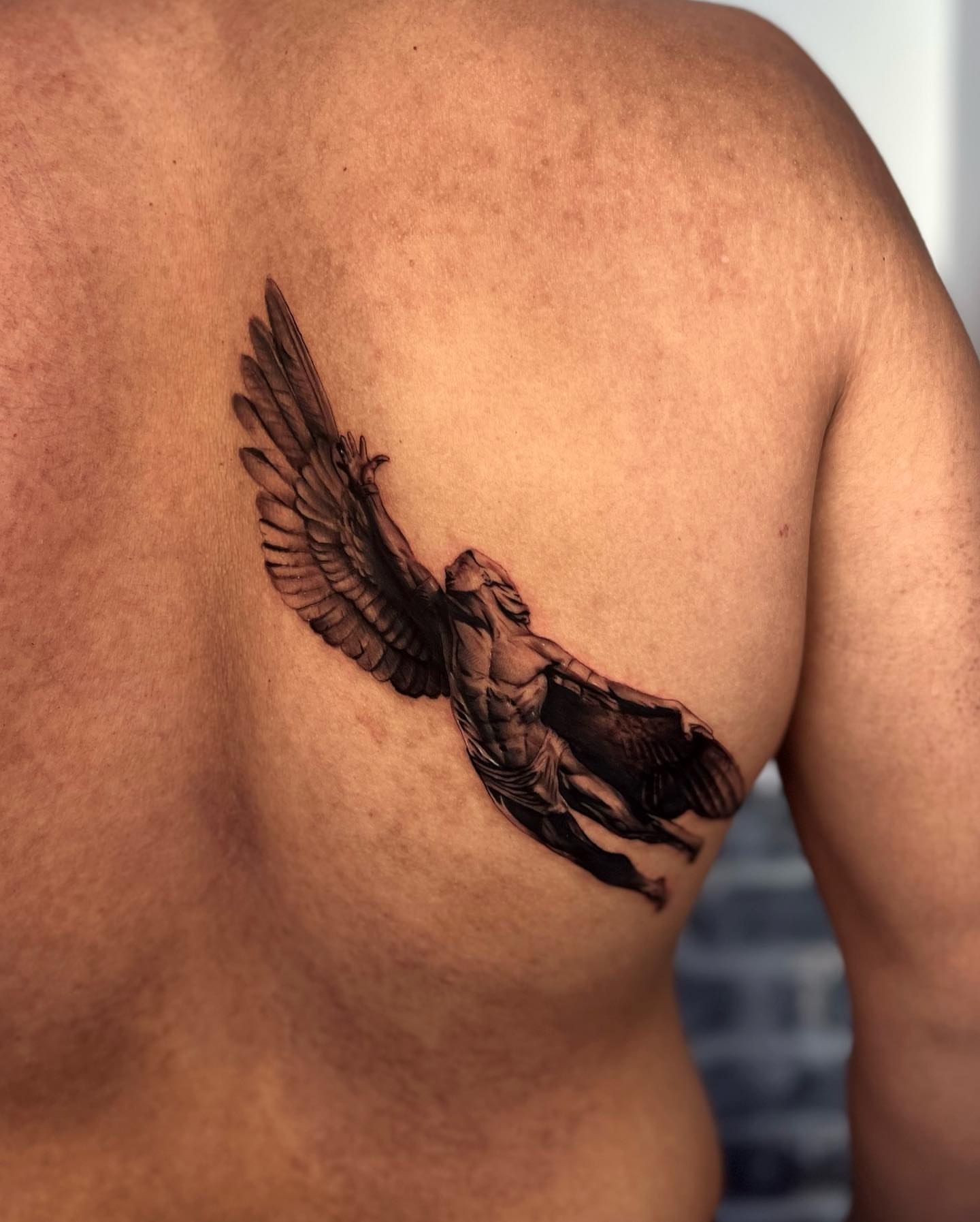 Winged figure black and grey tattoo on the back by Reena Pho, Nashville, Tennessee