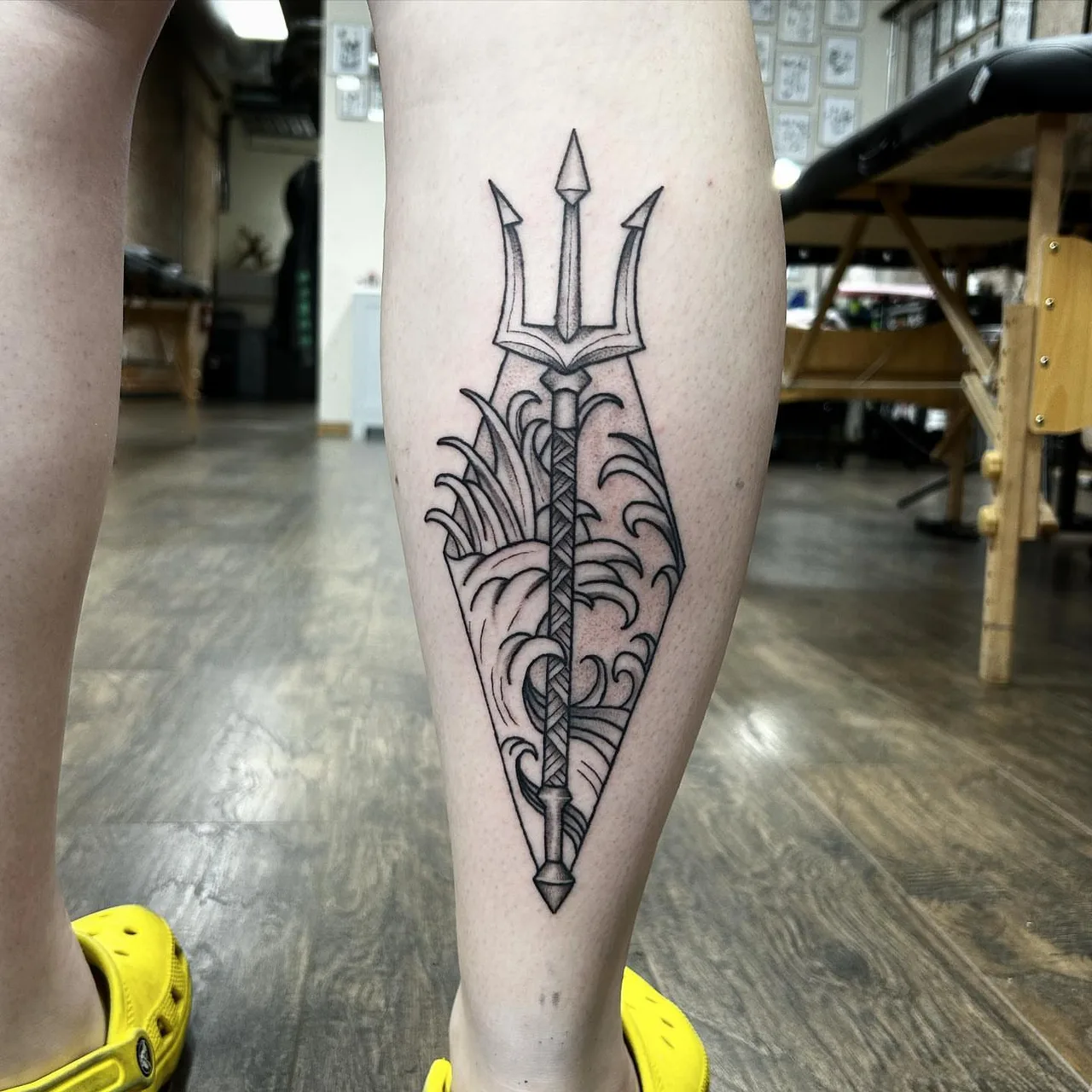Trident black and grey tattoo on the calf by Dylan Stevens
