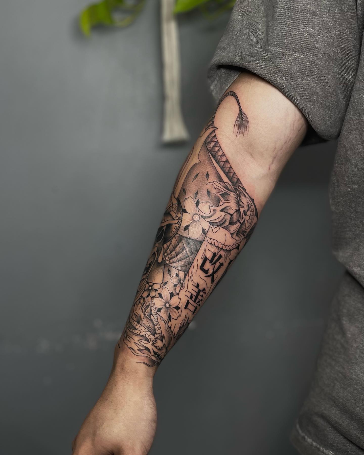 Floral and dragon black and grey tattoo on the forearm by Beans