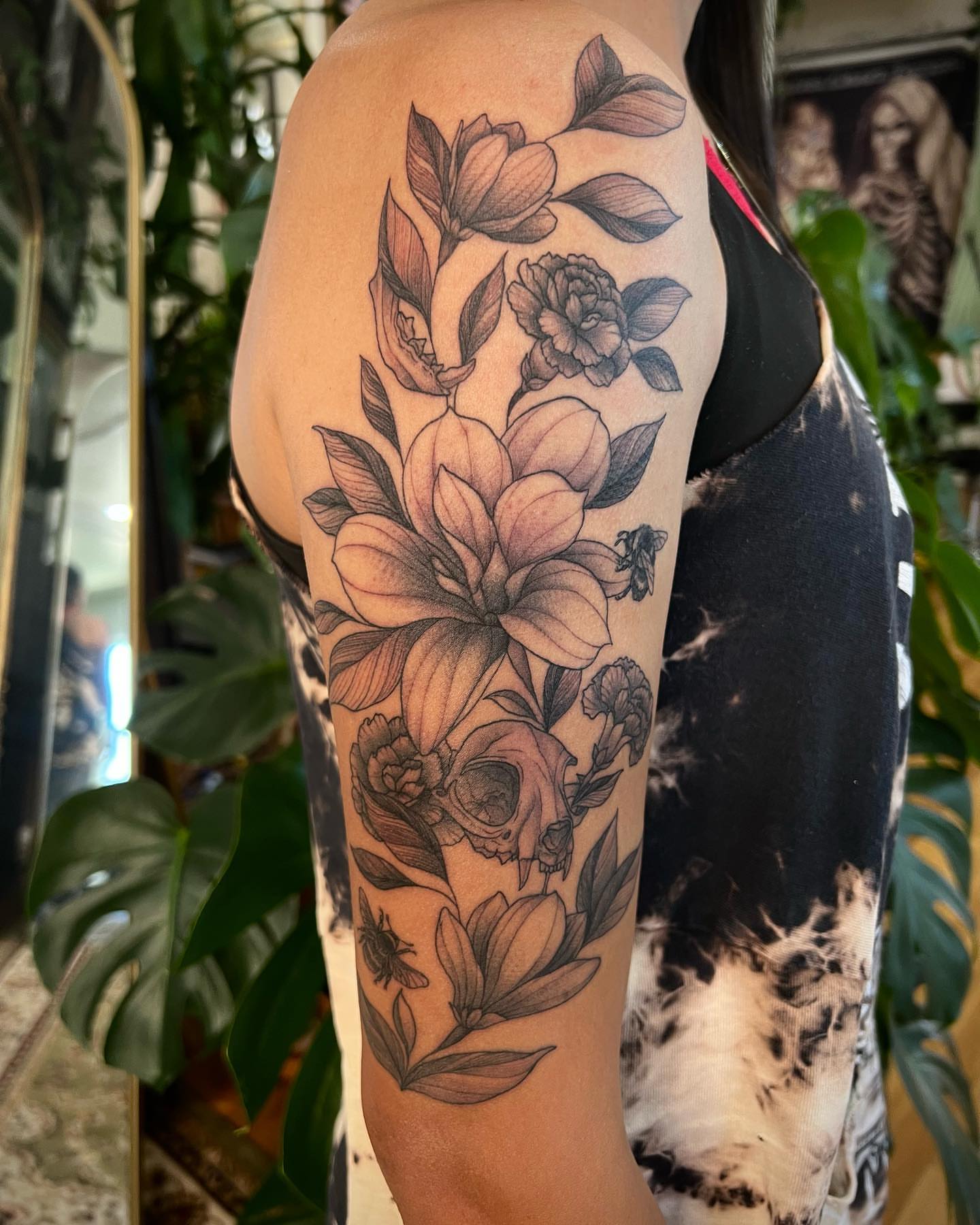 Floral arrangement with skull realism tattoo on the forearm by Mia Manzanedo