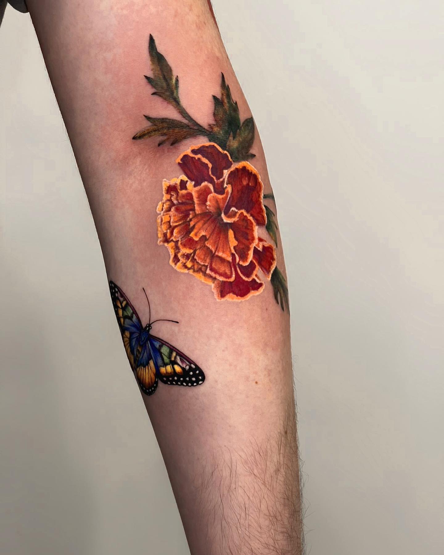 Marigold and butterfly realism tattoo on the forearm by Seattle Tattoo Artist PingPing, Seattle, Washington