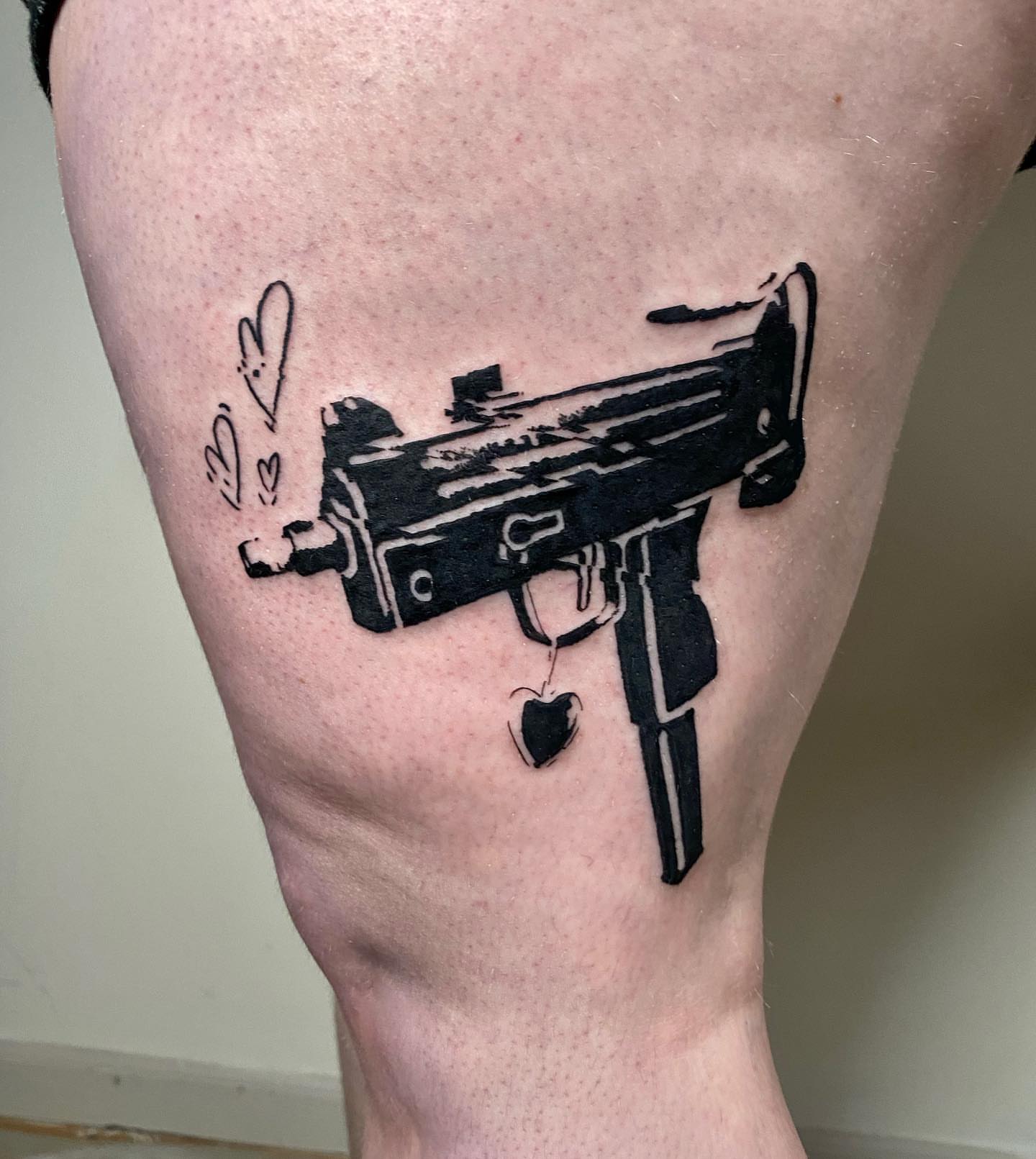 Machine gun black and grey tattoo on the thigh by Sarah