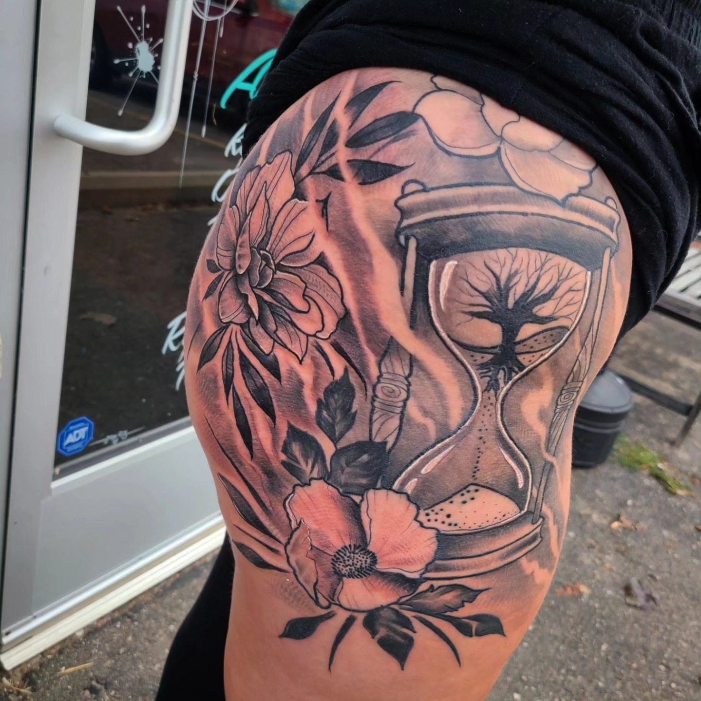 Hourglass and flowers realism tattoo on the thigh by David Johnson