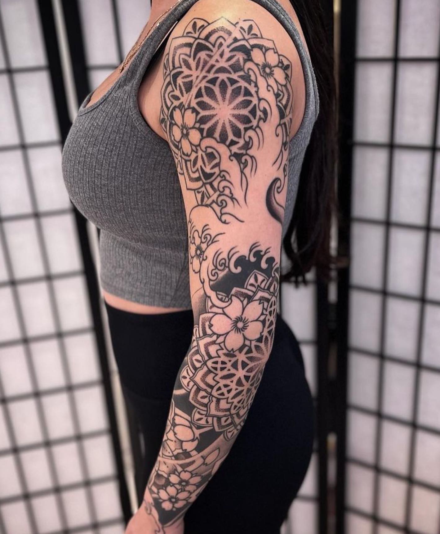 Mandala black and grey tattoo on the upper arm by Paul Schnell