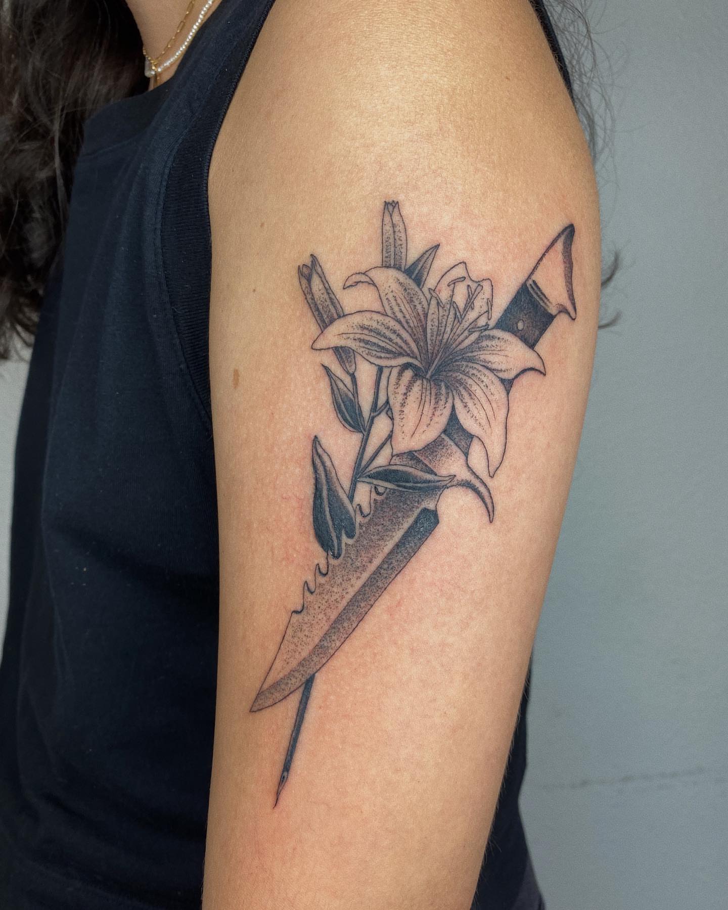 Lily and dagger black and grey tattoo on the forearm by Finley Jordan