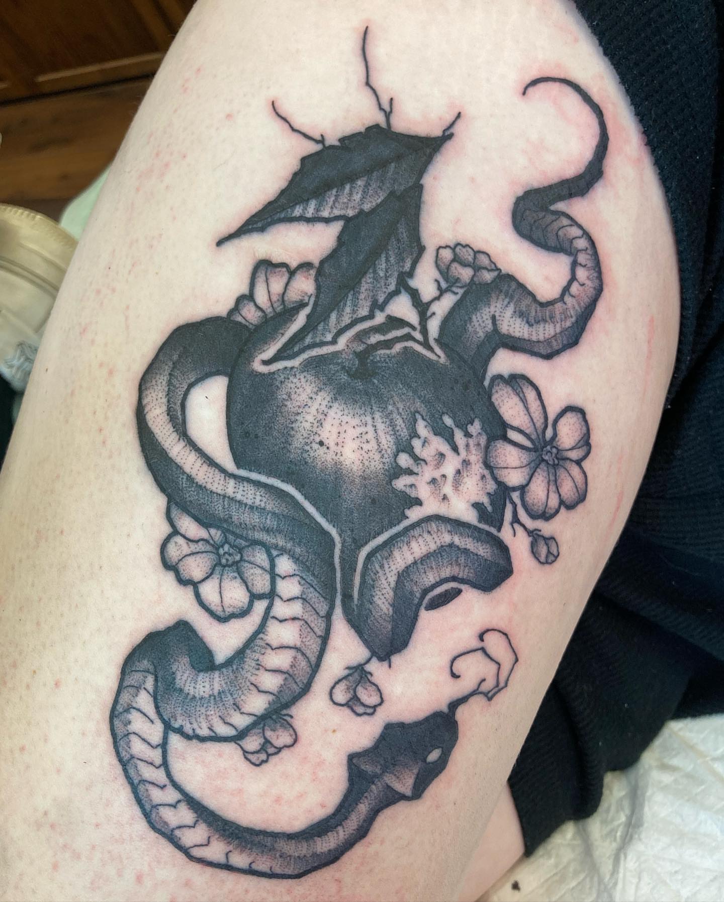 Dragon and flowers black and grey tattoo on the thigh by Griffin Benson
