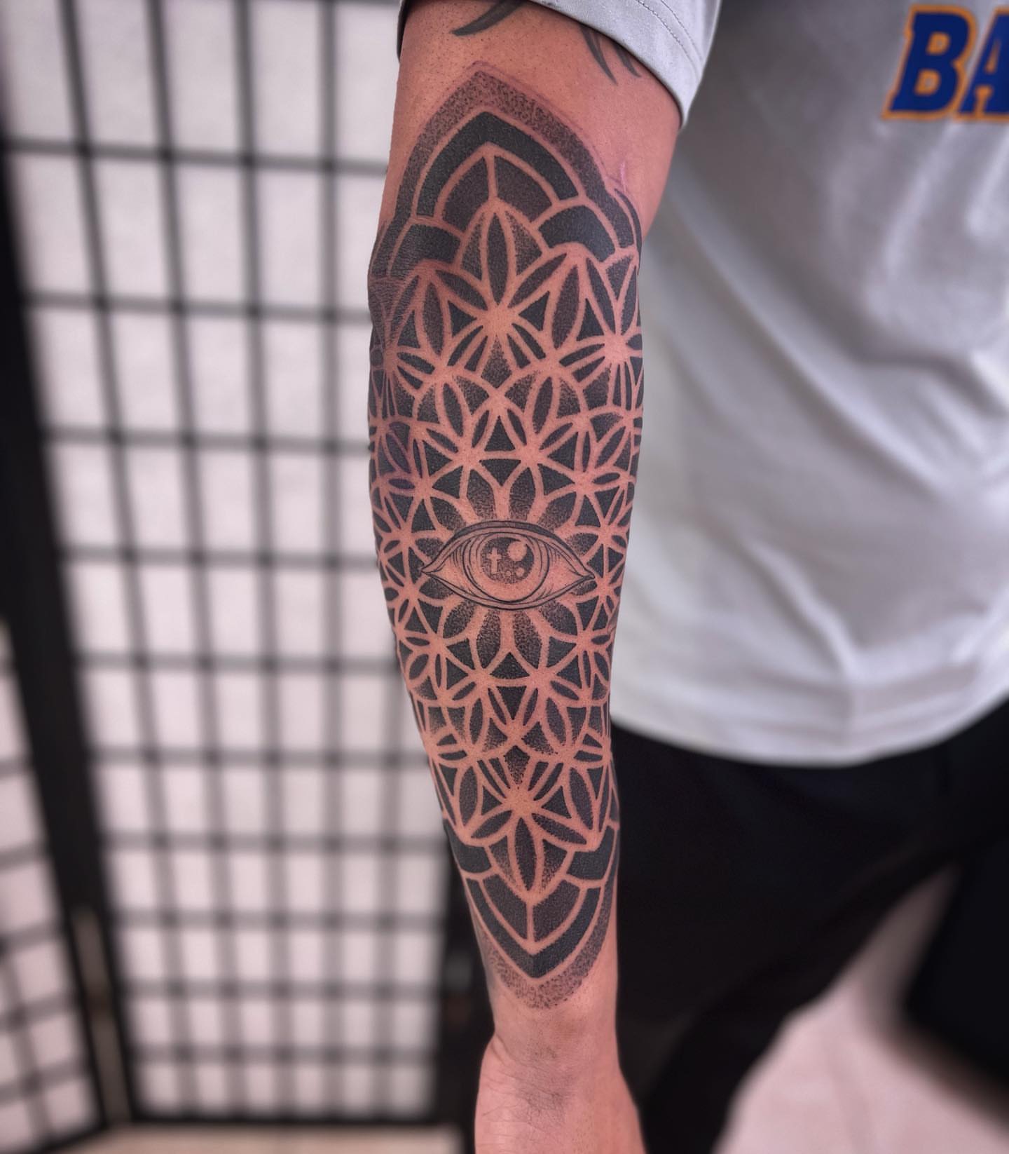 Eye within lotus dotwork tattoo on the forearm by Paul Schnell
