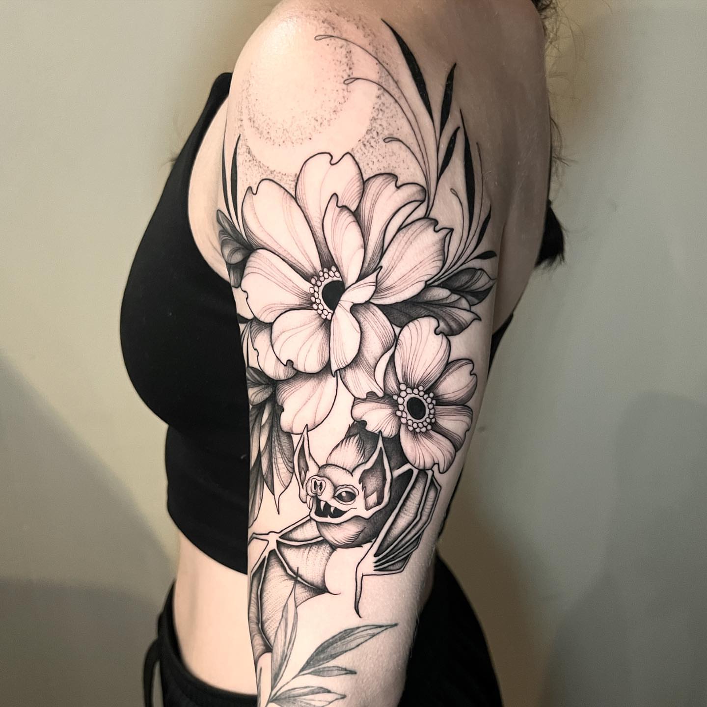 Flowers and bat realism tattoo on the upper arm by Chelsea Darling