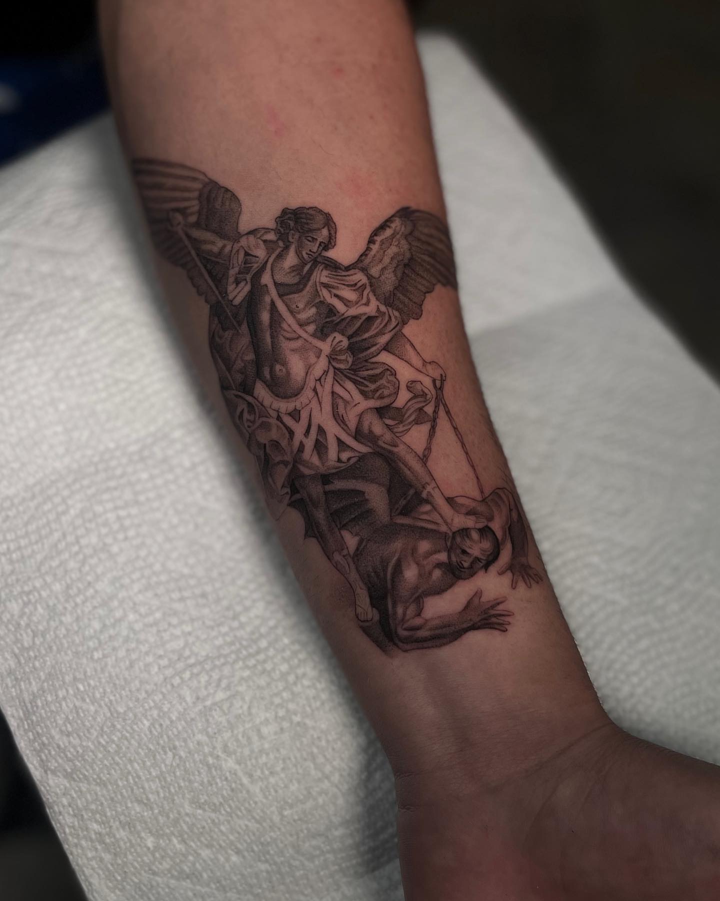 Angel and fallen figure realism tattoo on the forearm by Vanessa Valdivia