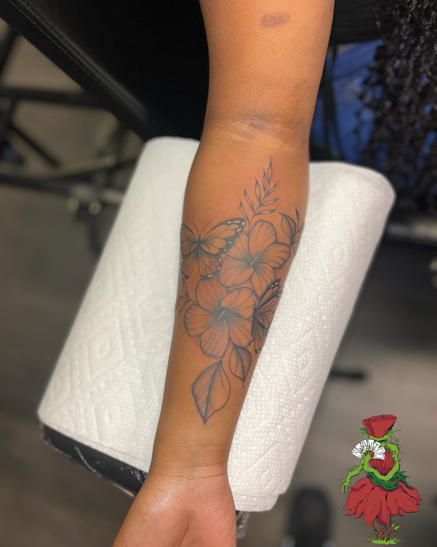 Flowers and butterflies black and grey tattoo on the forearm by Marques Neal
