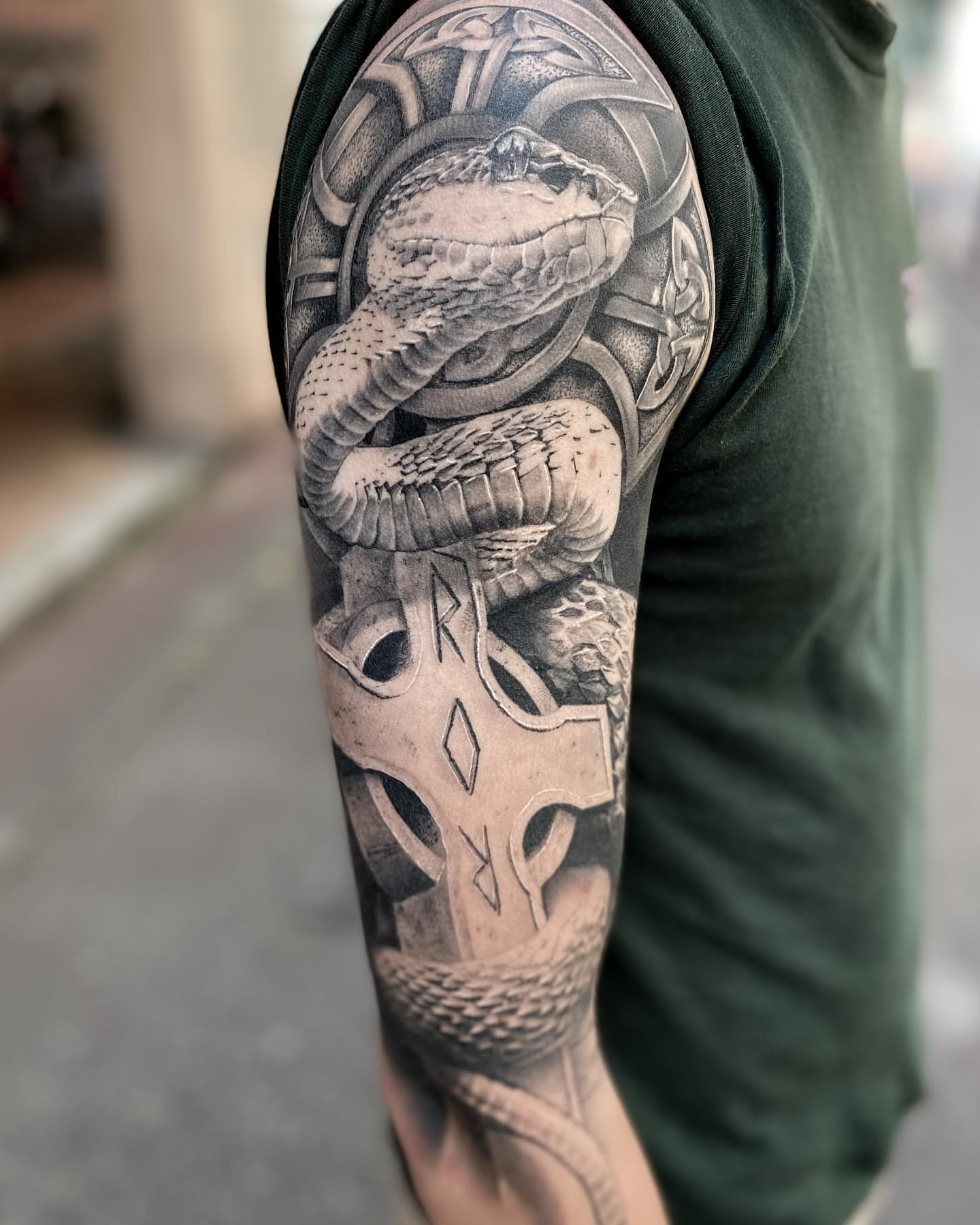 Snake and cross realism tattoo on the upper arm by Eltche Art Tattoo