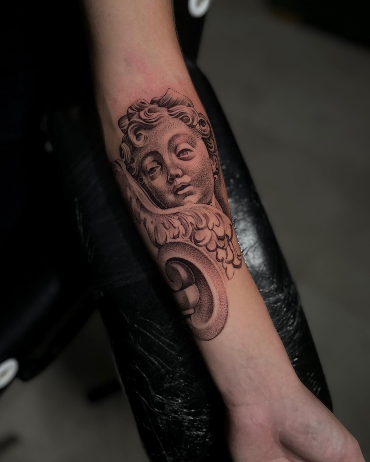 Angel head black and grey tattoo on the forearm by Vanessa Valdivia