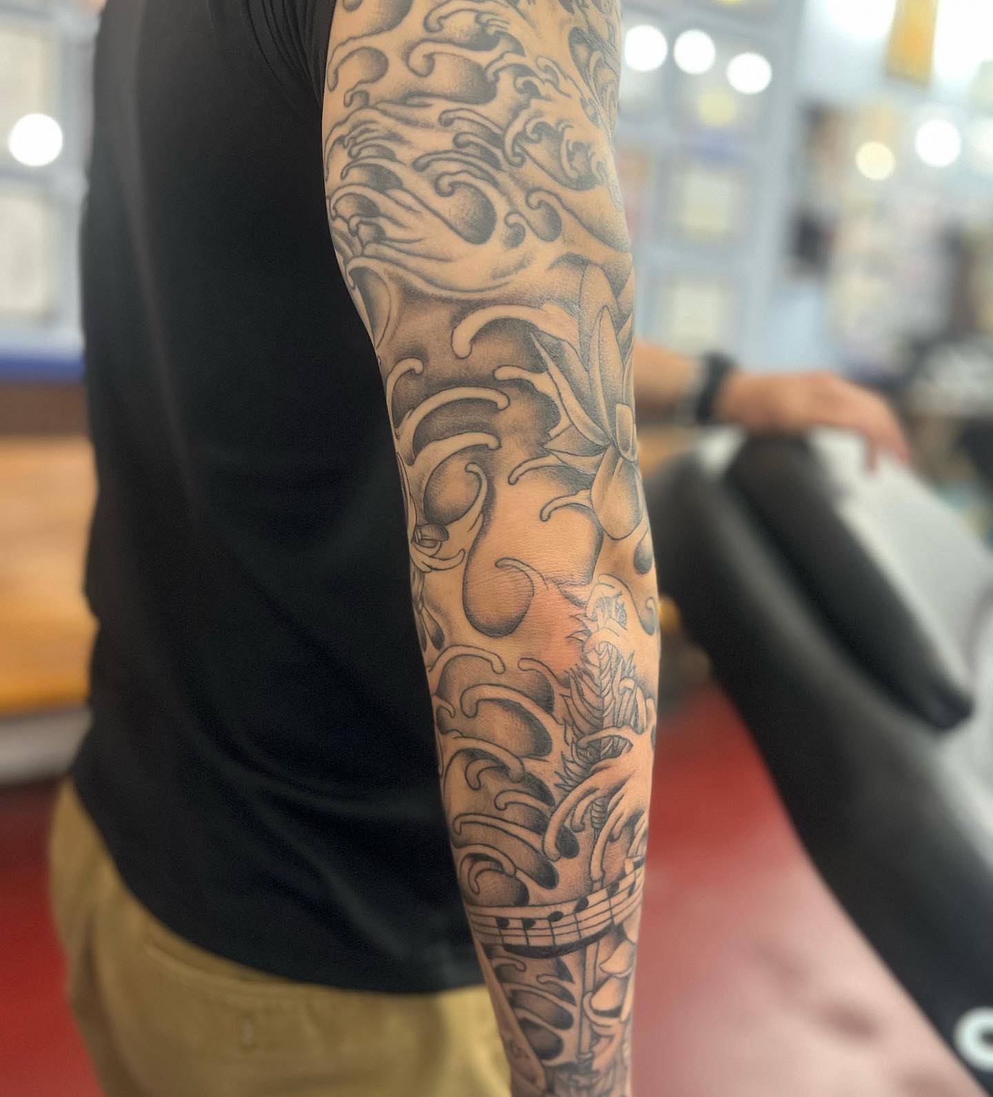 Waves and lotus black and grey tattoo on the forearm by IdleHandsFlex, New Orleans, Louisiana