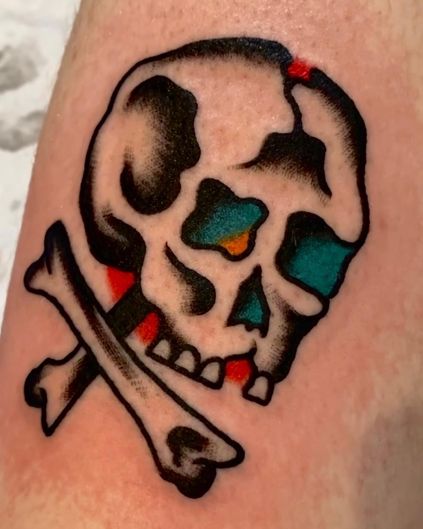Skull and crossbones American traditional tattoo on the forearm by Dorian Grey Baker