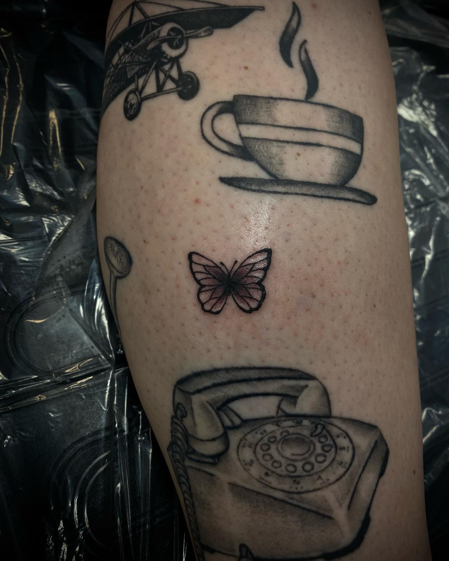 Aviator, coffee cup, butterfly, rotary phone black and grey tattoo on the forearm by ▪️JhonnyElias TATTOO ▪️