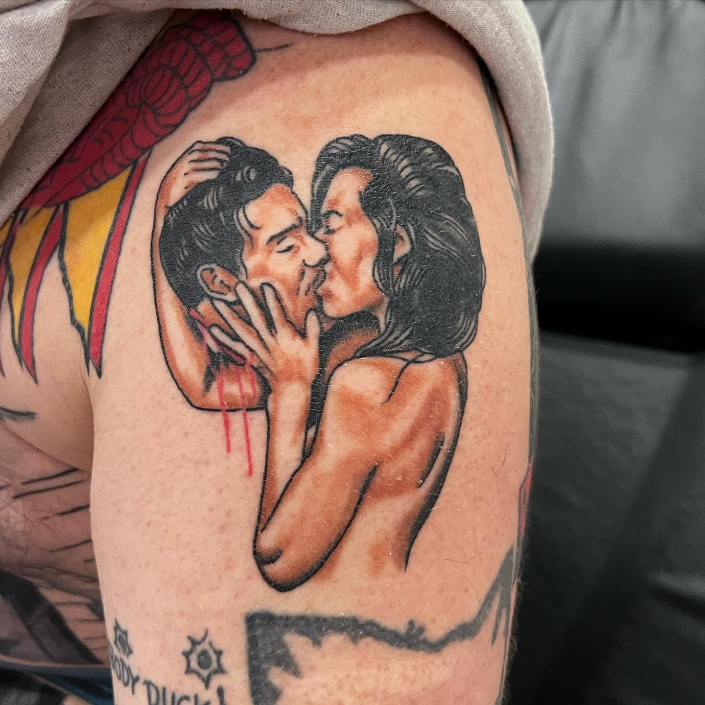 Kissing couple American traditional tattoo on the upper arm by Levi Cox, Powell, Ohio