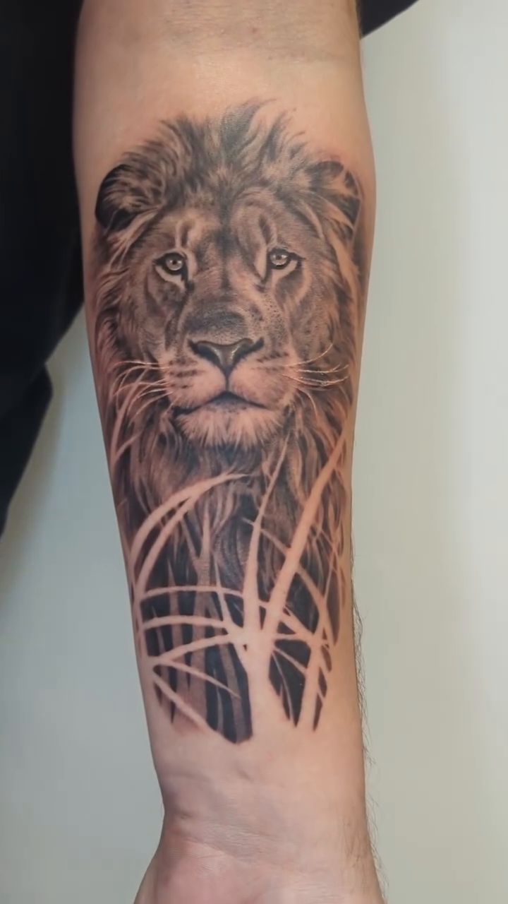 Lion portrait with grass realism tattoo by Sean Costello