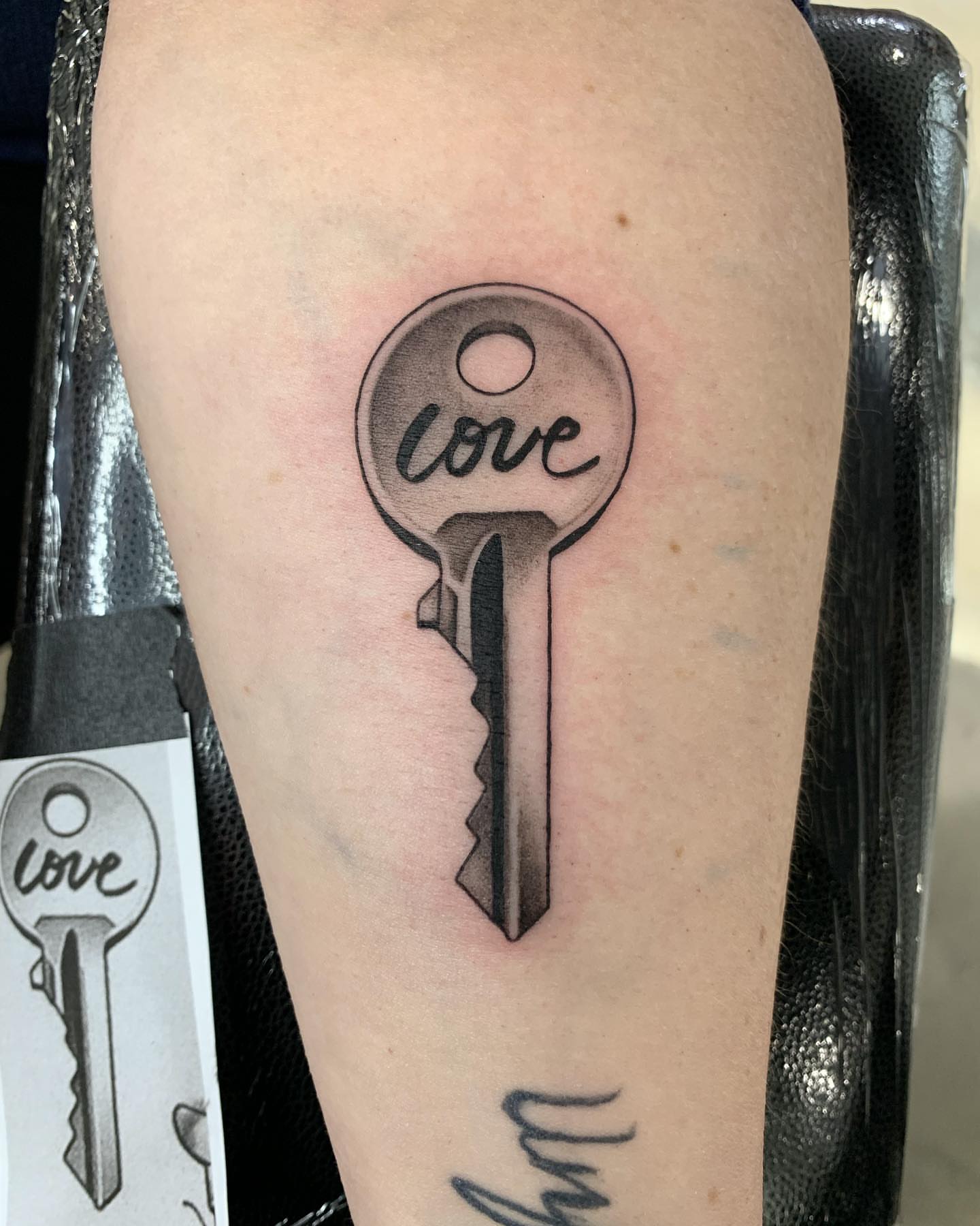 Key with 'love' written on it black and grey tattoo on the thigh by Winters Ashurst - St. George tattoo artist