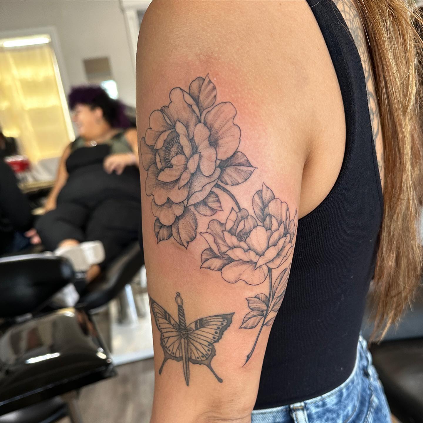 Flowers and butterfly black and grey tattoo on the upper arm by Stephen Hansen