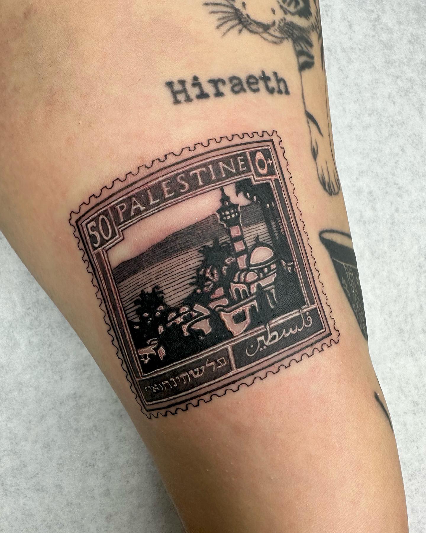 Palestine postage stamp black and grey tattoo on the forearm by Em Krieg