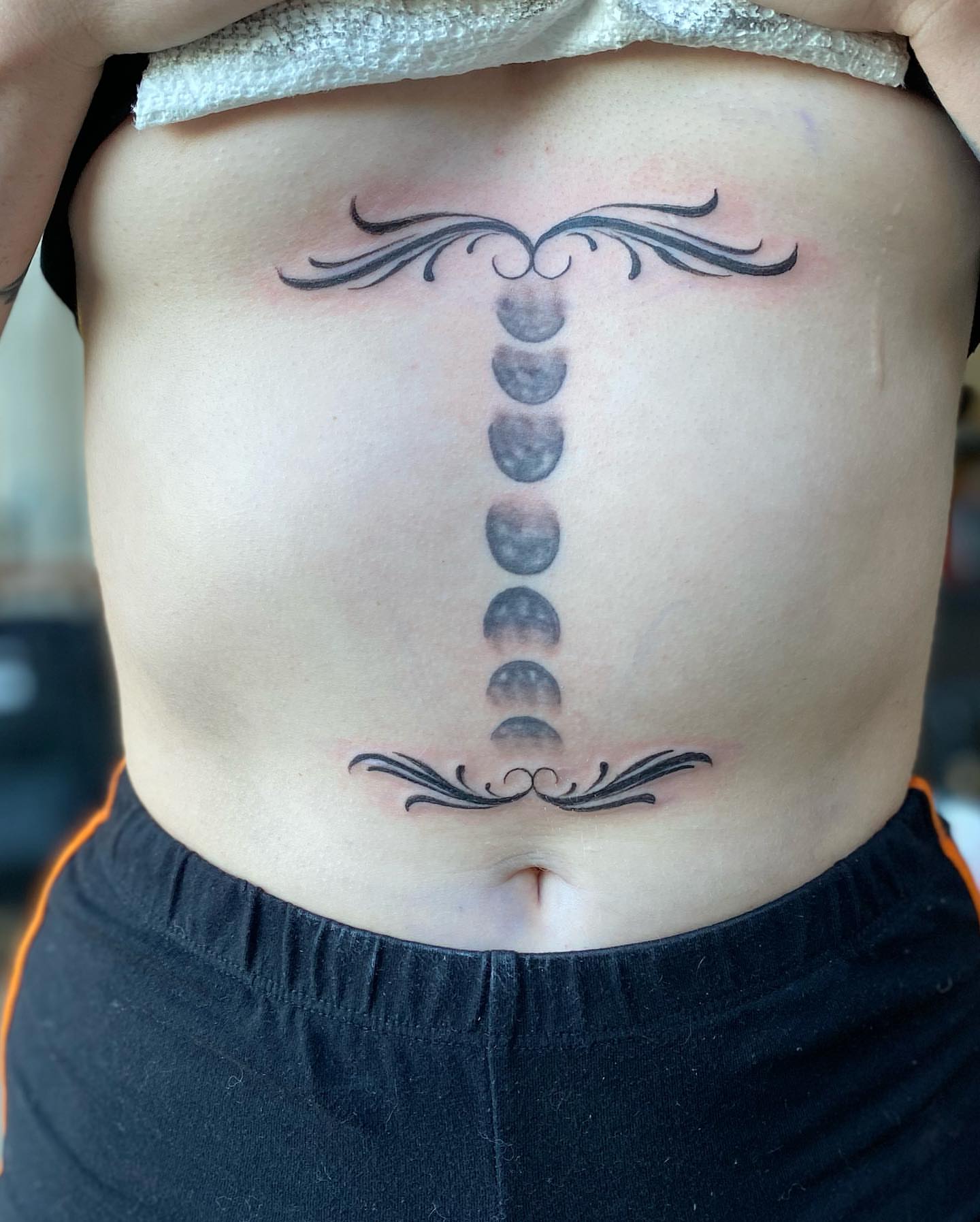 Moon phases dotwork tattoo on the ribs by Chino's Tattoos
