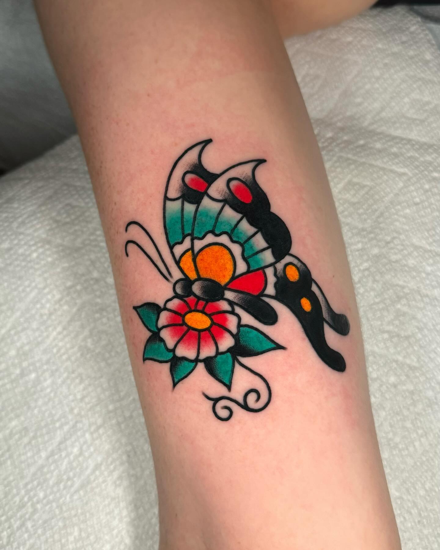 Butterfly and flower American traditional tattoo on the forearm by James Shepherd, Austin, Texas