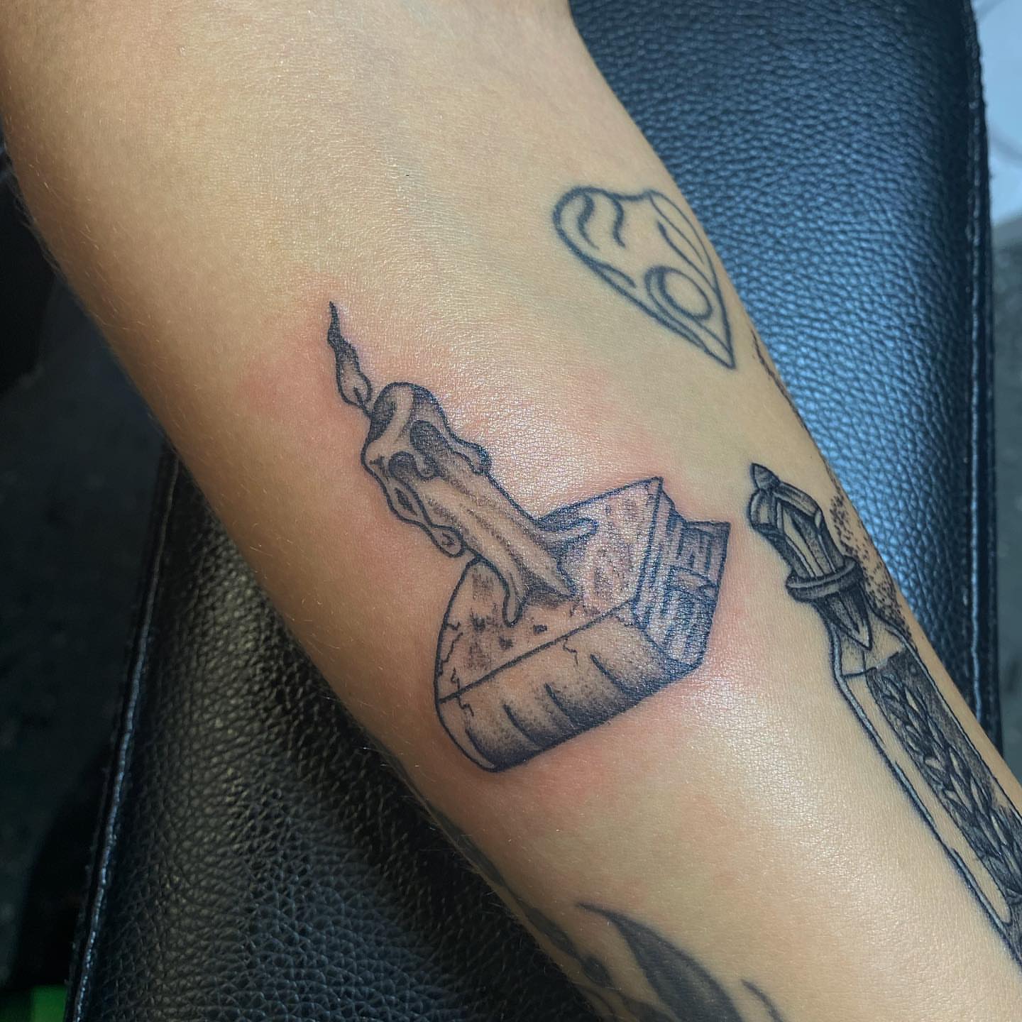 Skull and candle black and grey tattoo on the forearm by Maddie Neibert