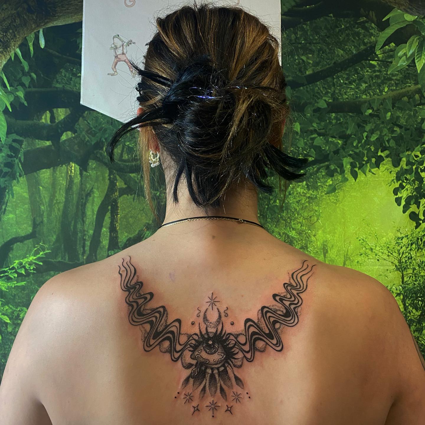 Eye and wavy lines black and grey tattoo on the back by Maddie Neibert