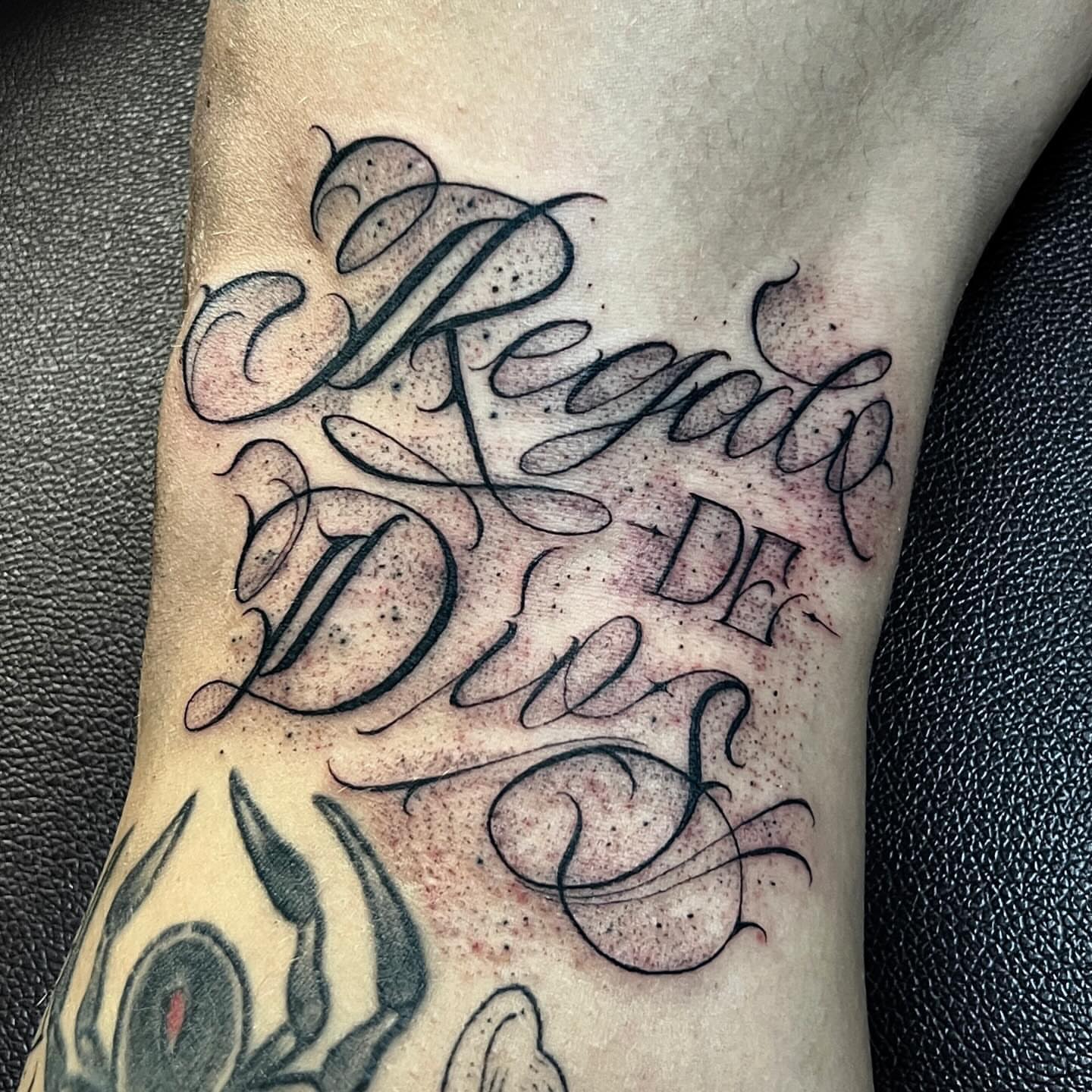 Regalo de Dios lettering script tattoo on the forearm by Joey Moreno