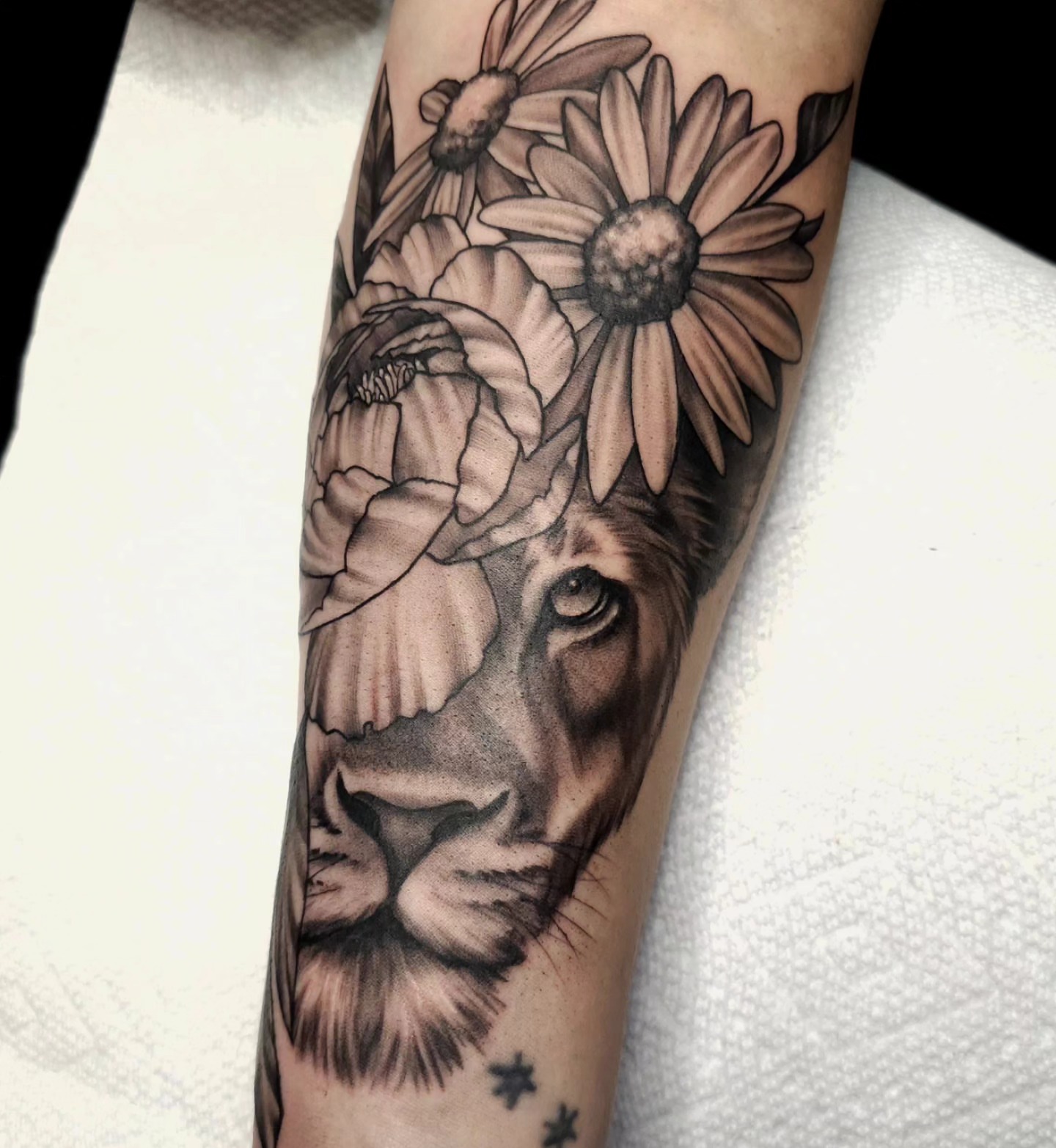 Lion with flowers realism tattoo on the forearm by Gabrielle Nicole Soucie