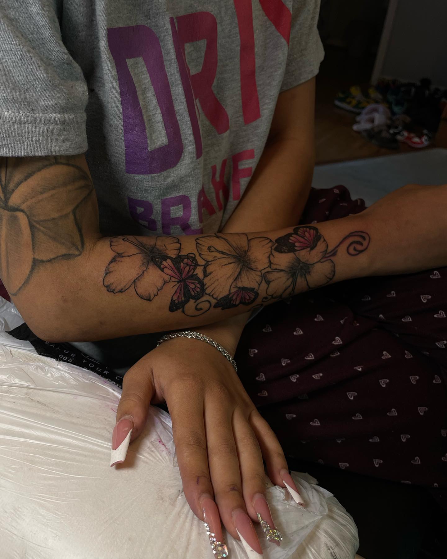 Flowers and butterflies black and grey tattoo on the forearm by Dinero Inks
