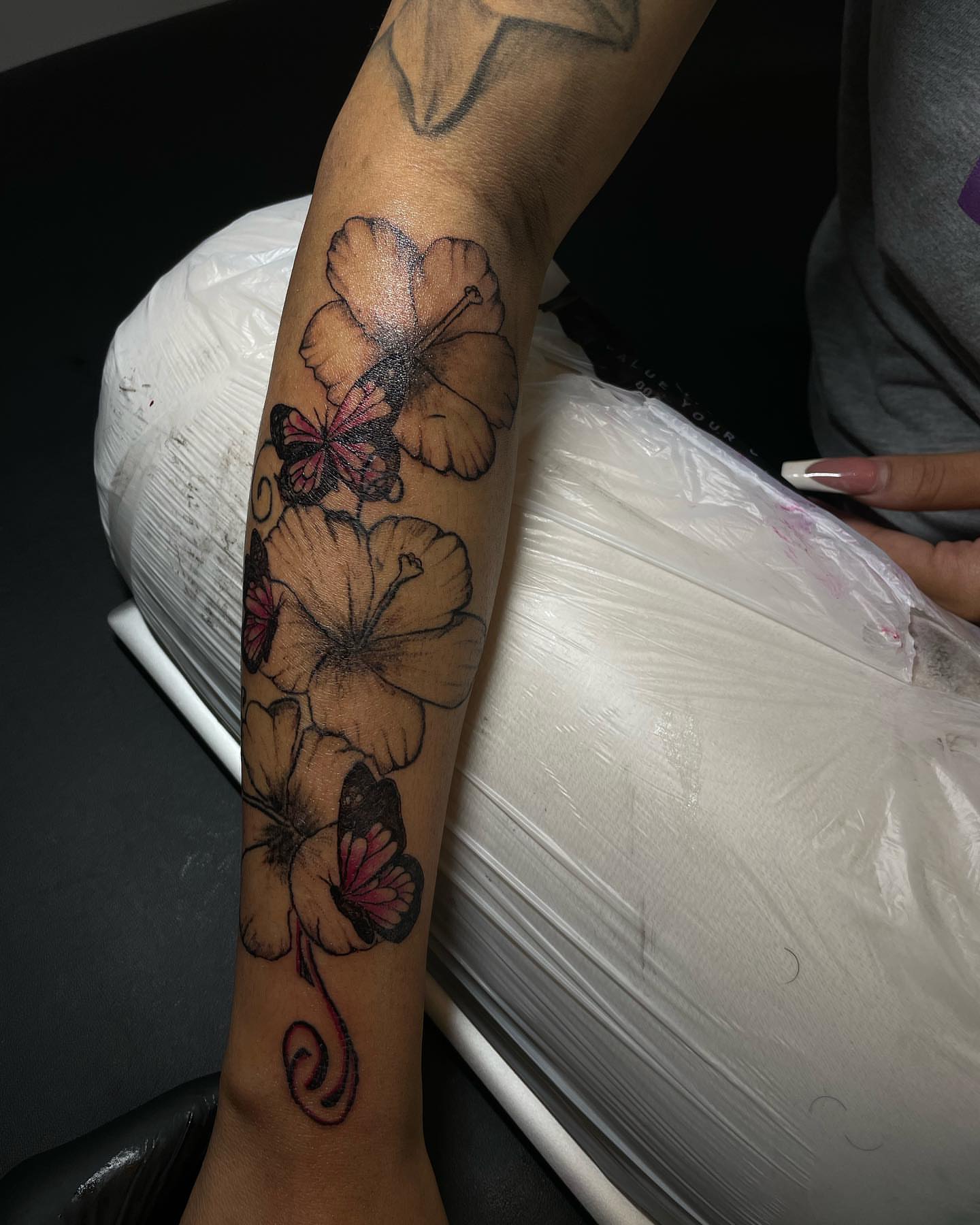 Flowers and butterflies black and grey tattoo on the forearm by Dinero Inks