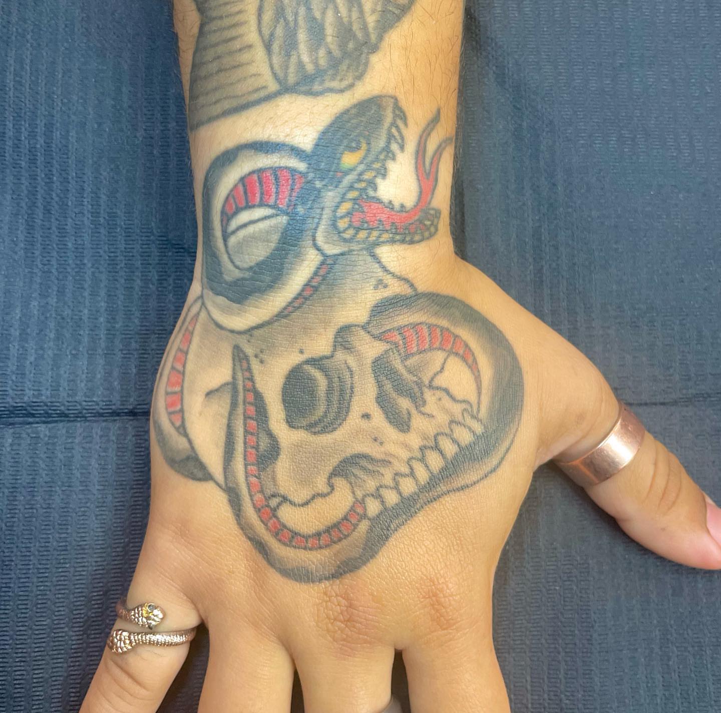 Skull and snake American traditional tattoo on the hand by Seth Griffin