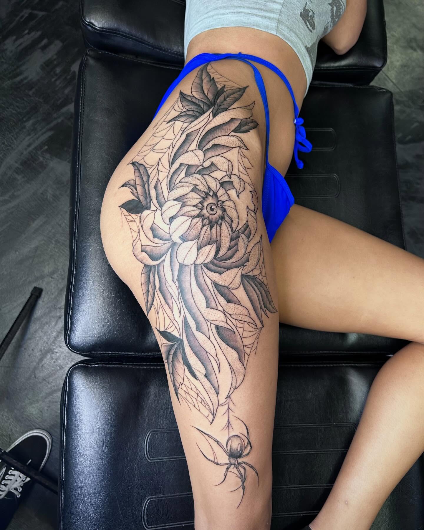 Flower and spider black and grey tattoo on the thigh by Colby McClain