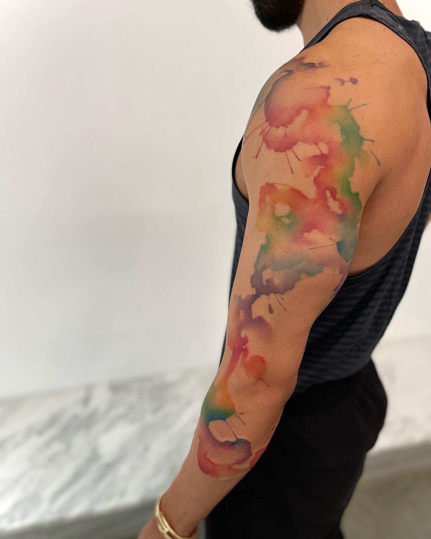 Watercolor splash watercolor tattoo on the upper arm by Georgia Grey