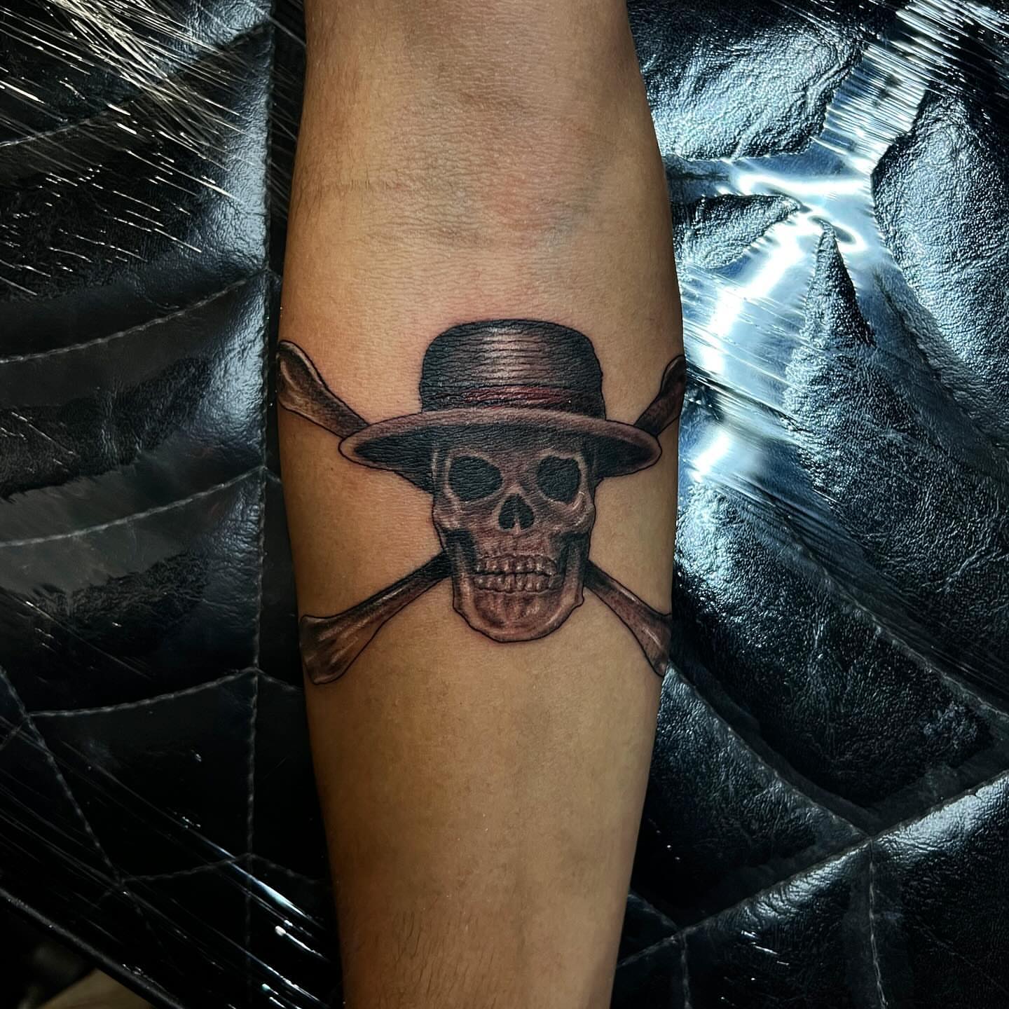 Skull wearing hat black and grey tattoo on the forearm by Joey Moreno