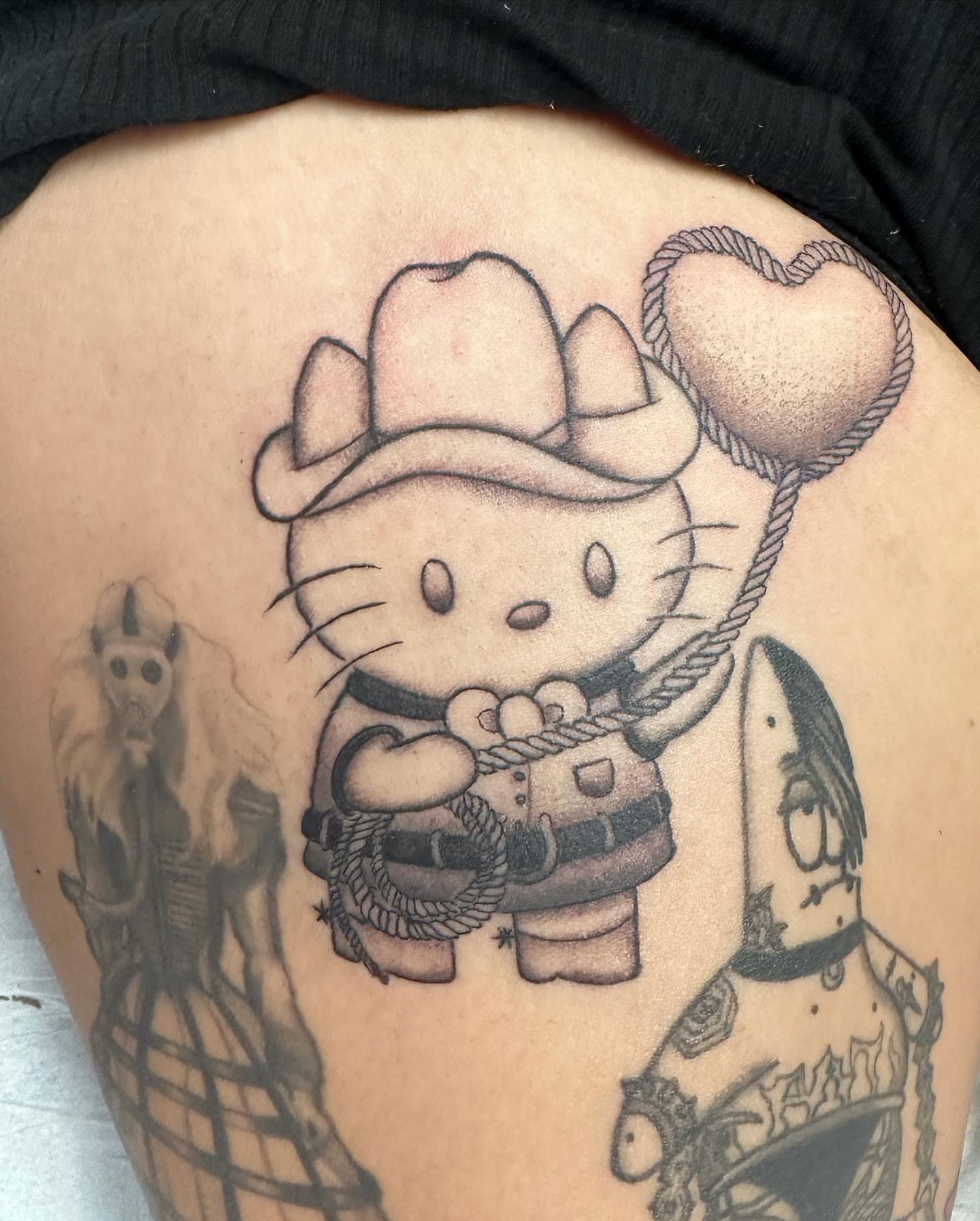 Cowboy hello kitty black and grey tattoo on the thigh by Mika