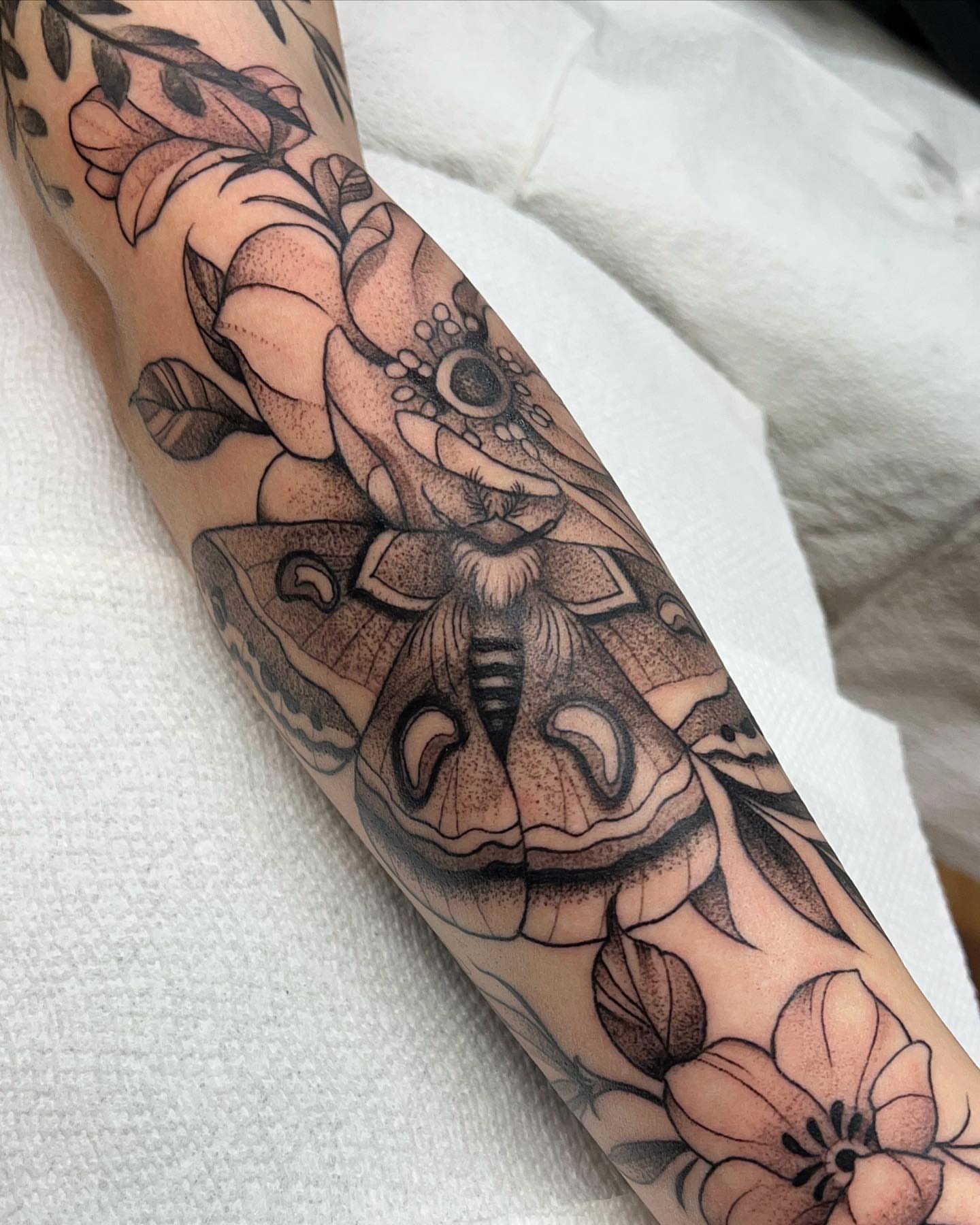 Moth and flowers realism tattoo on the forearm by Lauren Peltz