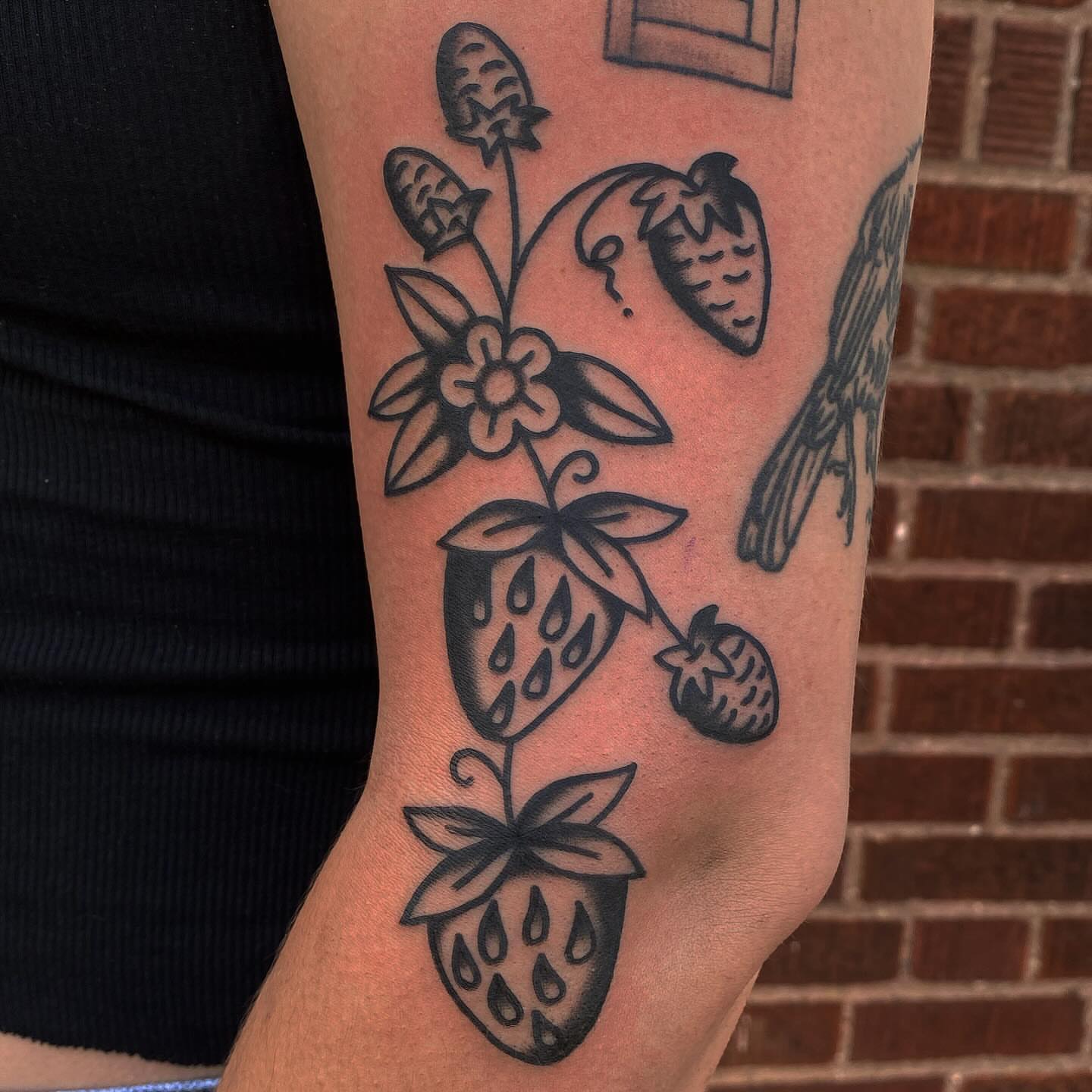 Strawberries and flowers black and grey tattoo on the forearm by Erin Chambers