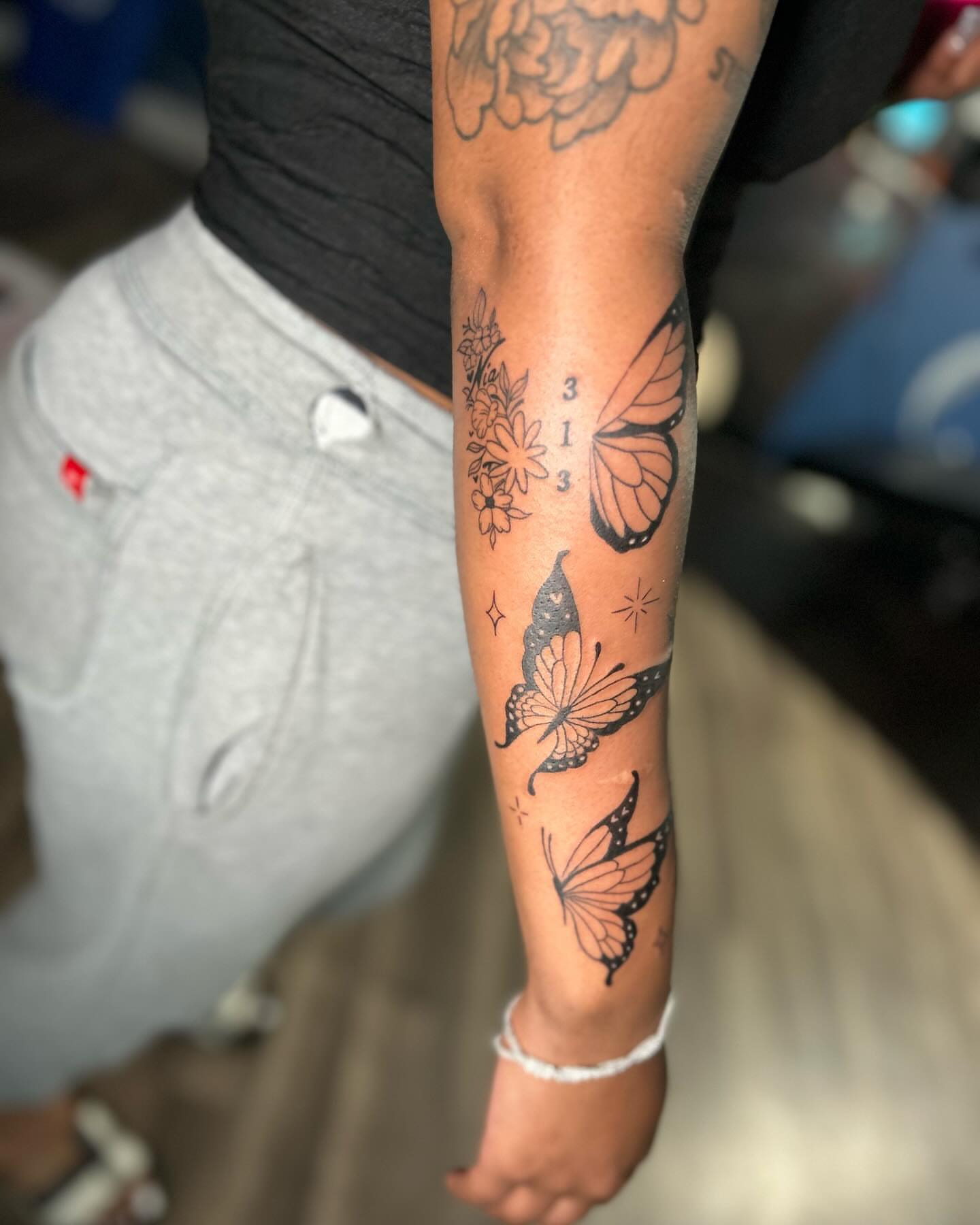 Butterflies and flowers black and grey tattoo on the forearm by Kells