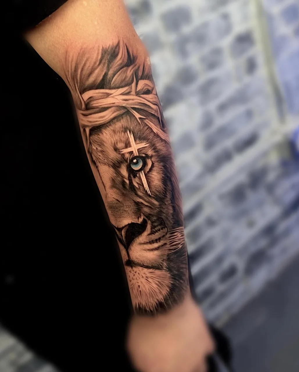Lion with cross realism tattoo on the forearm by Amilia Gullotta