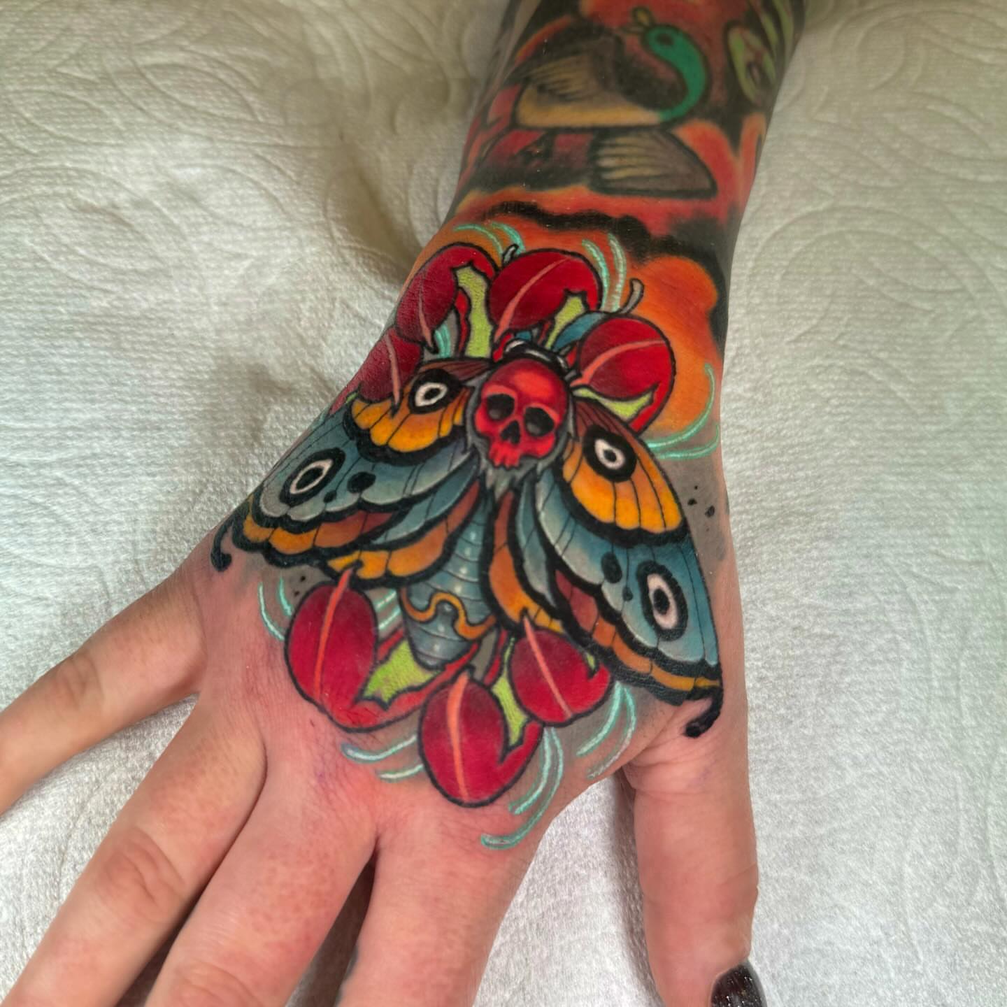 Butterfly and skull American traditional tattoo on the hand by Jon Leighton