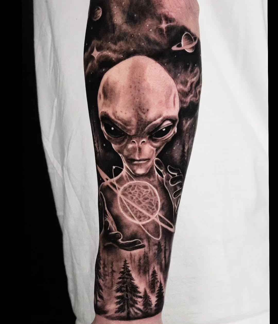 Alien holding a planet surrealism tattoo on the forearm by Brandon Rabago, Fort Worth, Texas